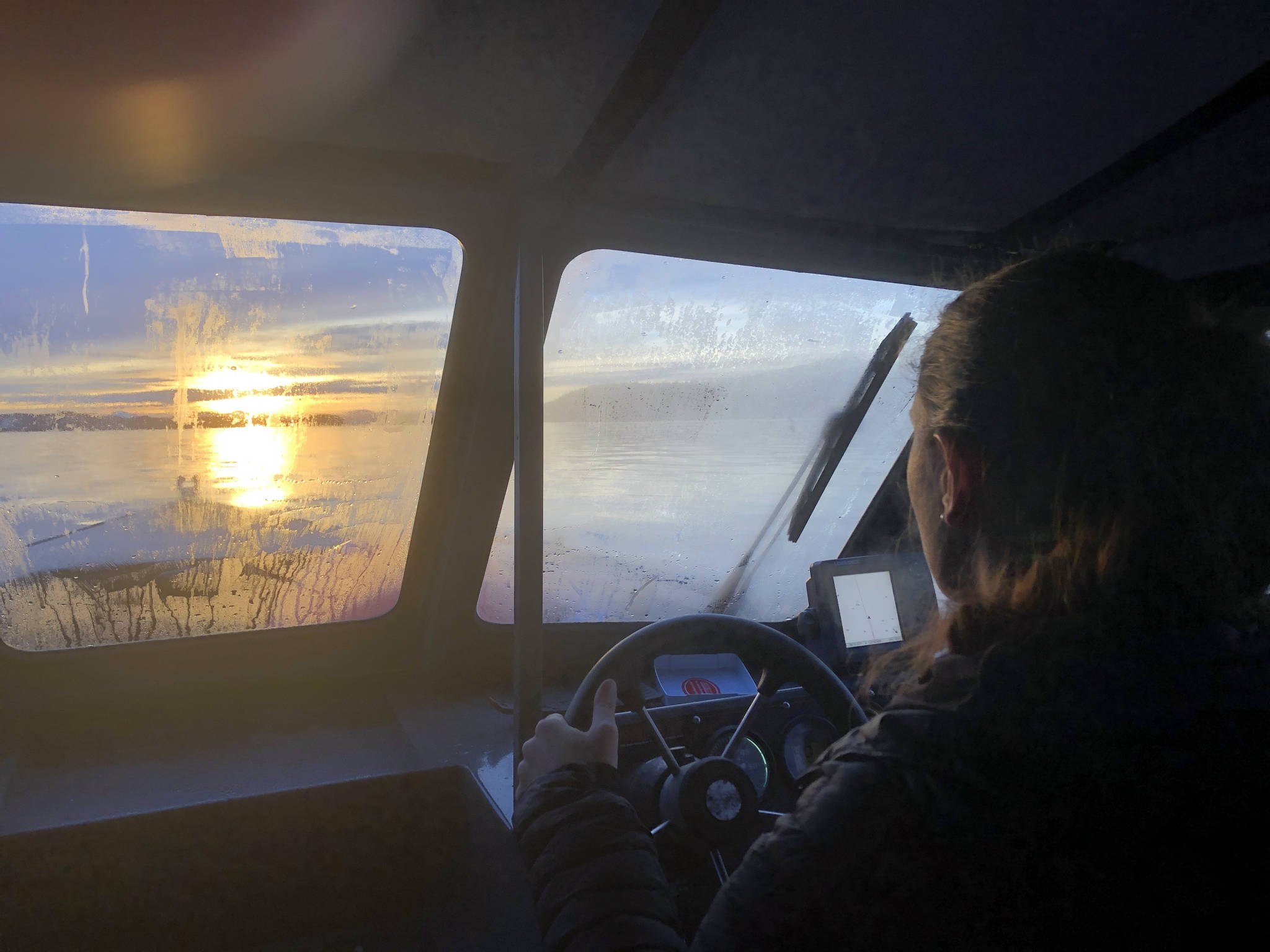 The authors fiancee, Abby, navigates their boat in the fading afternoon light. Shortly after returning to the dock, an otter took up residence aboard. (Jeff Lund / For the Juneau Empire)
