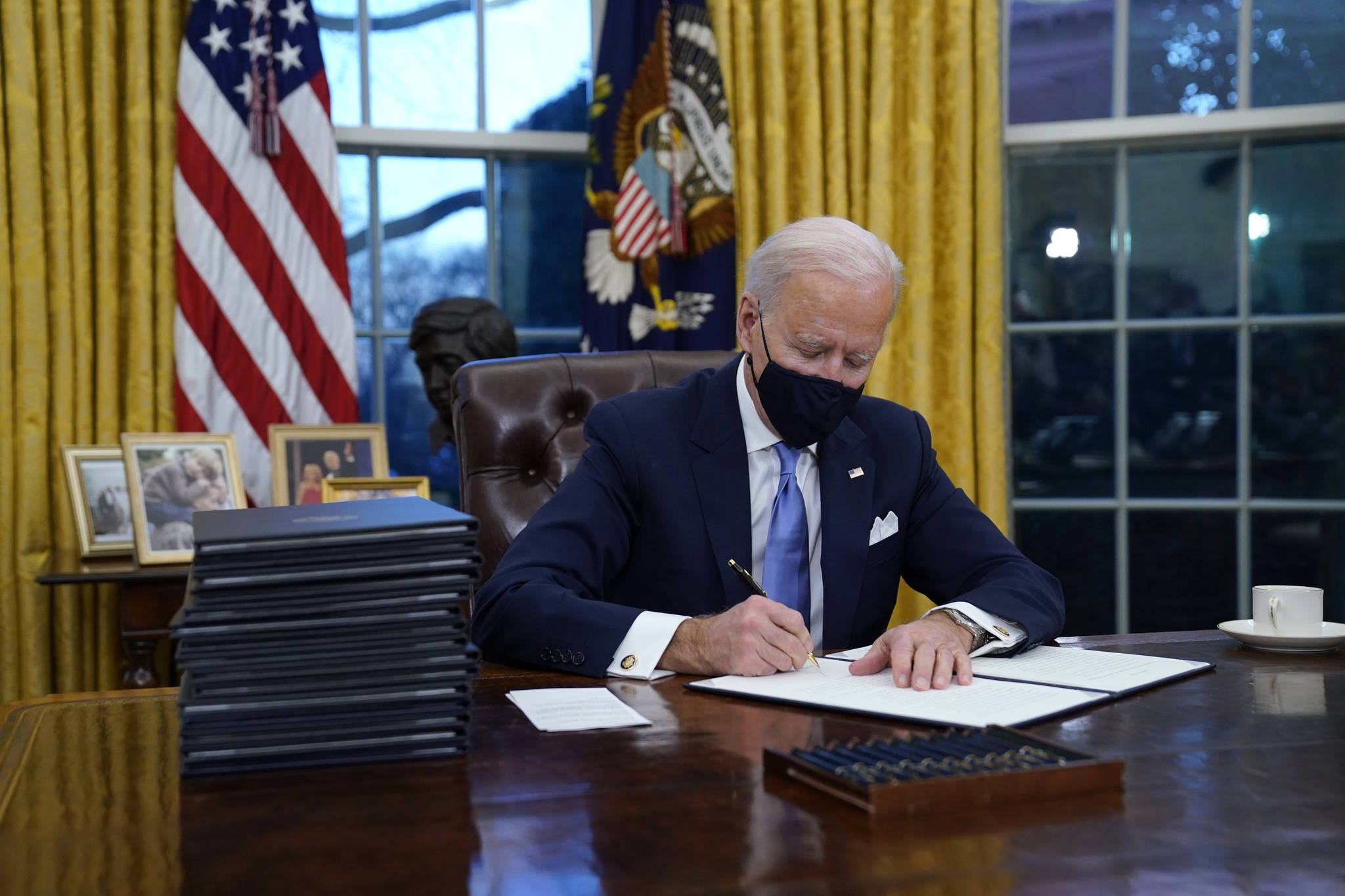 President Joe Biden signs his first executive order in the Oval Office of the White House on Wednesday, Jan. 20, 2021, in Washington. (AP Photo / Evan Vucci)