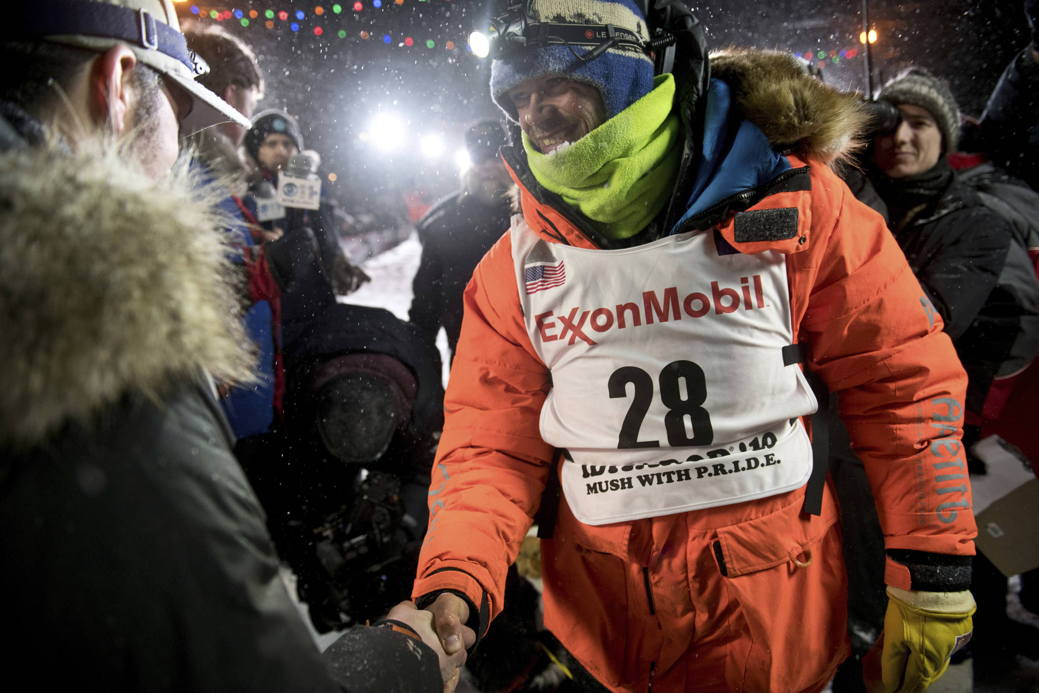 Joar Leifseth Ulsom, right, wearing a bib with ExxonMobil lettering on it, congratulates Peter Kaiser on his win in the Iditarod Trail Sled Dog Race in Nome, Alaska. The world’s most famous sled dog race has lost another major sponsor as the Iditarod prepares for a scaled-back version of this year’s race because of the pandemic, officials said Thursday, Jan. 21, 2021. ExxonMobil confirmed to The Associated Press that the oil giant will drop its sponsorship of the race. (Marc Lester / Anchorage Daily News)