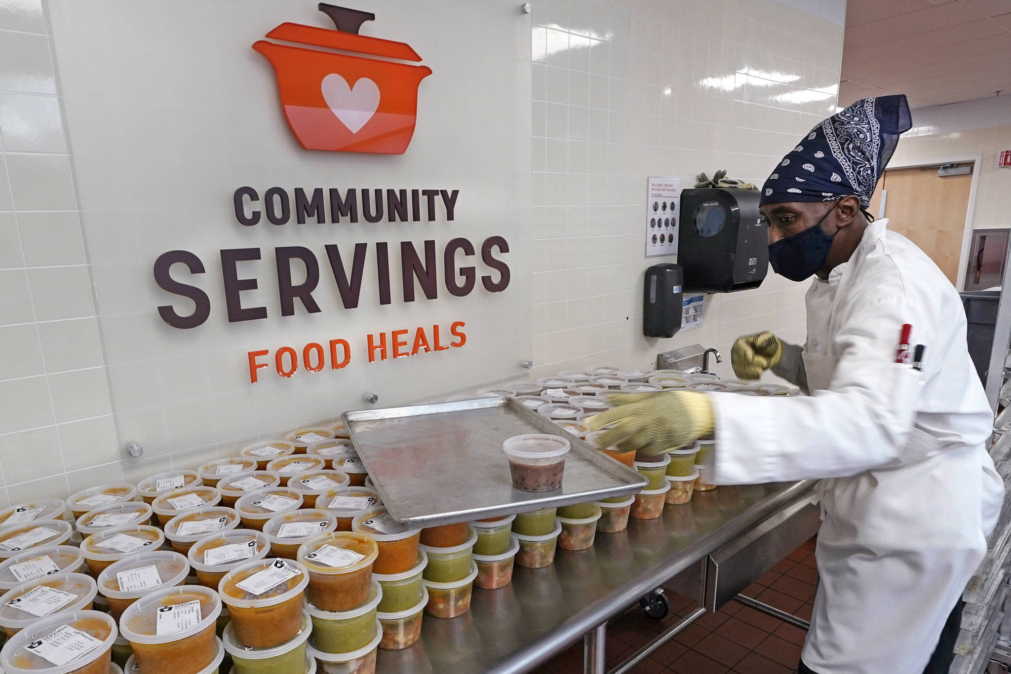 Chef Jermaine Wall stacks containers of soups at Community Servings, which prepares and delivers scratch-made, medically tailored meals to individuals & families living with critical & chronic illnesses, Tuesday, Jan. 12, 2021, in the Jamaica Plain neighborhood of Boston. Food is a growing focus for insurers as they look to improve the health of the people they cover and cut costs. Insurers first started covering Community Servings meals about five years ago, and CEO David Waters says they now cover close to 40%. (AP Photo / Charles Krupa)