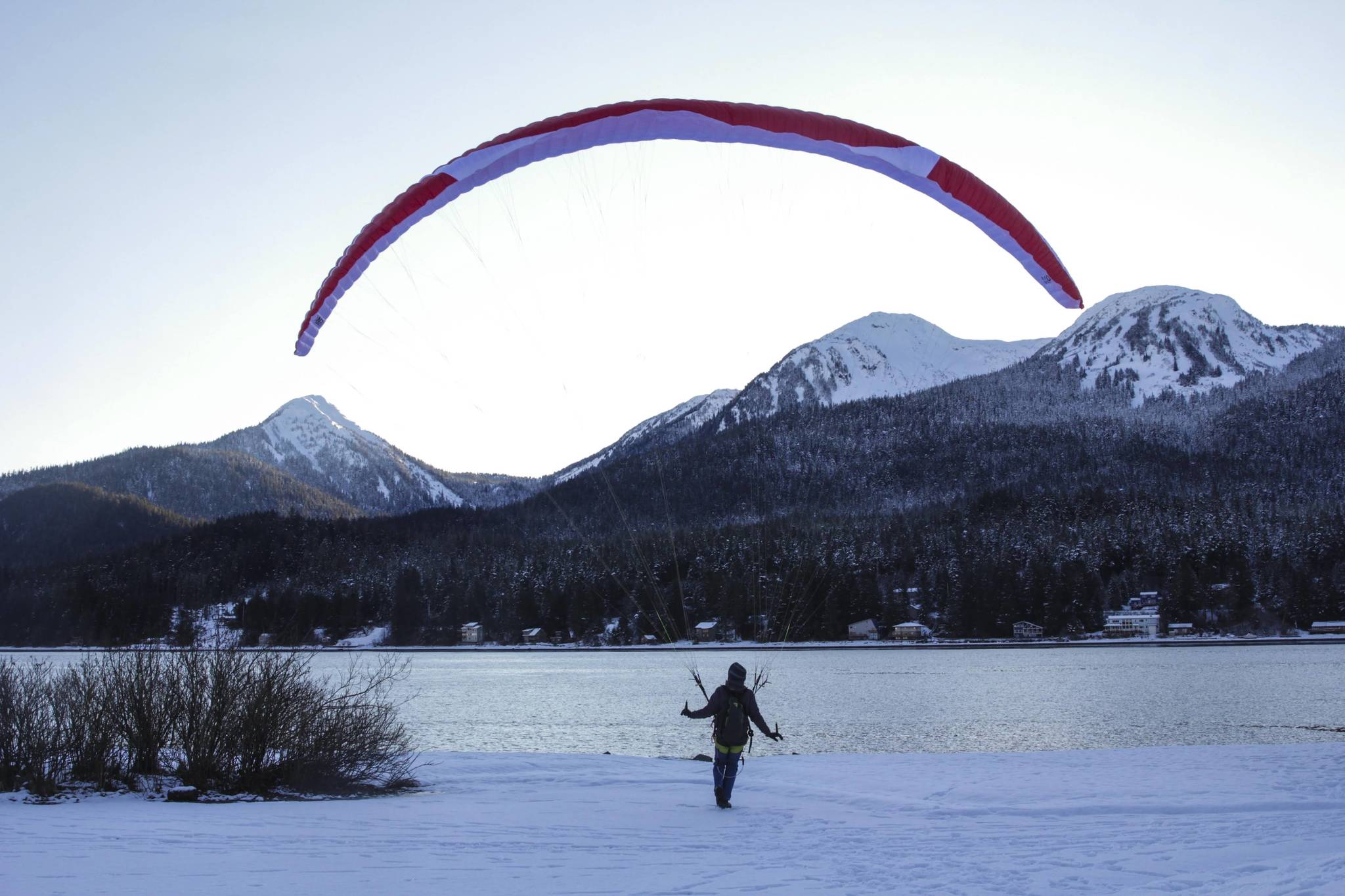 Robert Fawcett familiarizes himself with a new wing alongside the Gastineau Channel at Wayside Park on Jan. 27, 2021. “When you’re up on the mountain, you get more variables, more winds and gusts,” Fawcett said in a brief interview. “The same controls you use in the air, you use on the ground. It’s always good to practice.” Fawcett said he’d taken the wing off a mountain on Monday. “I like the hike up,” Fawcett said. “I don’t like the hike down.” (Michael S. Lockett / Juneau Empire)