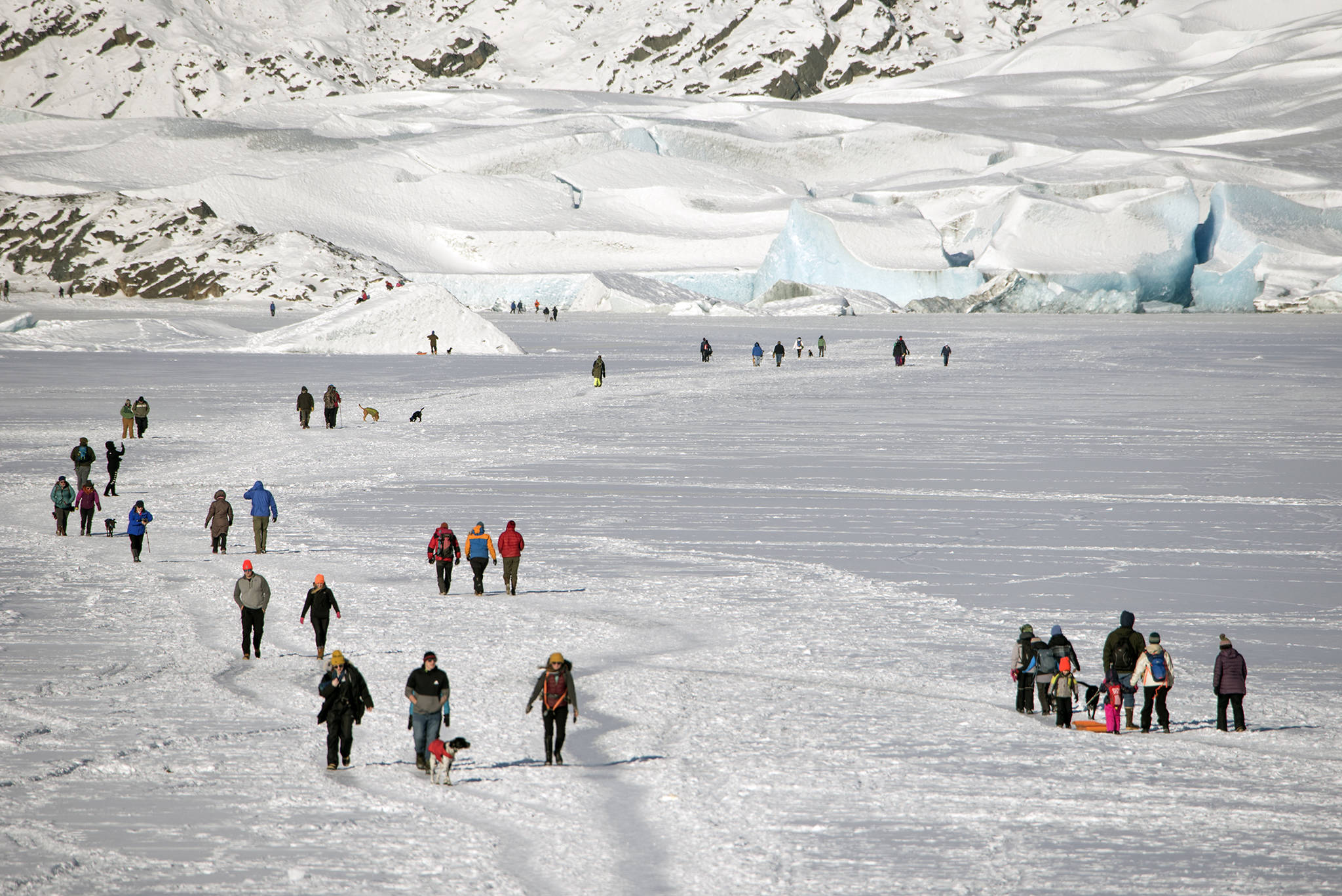 Walkers head across the frozen Mendenhall Lake to the ice caves at the glacier on Feb. 11, 2021. (Courtesy Photo / Kenneth Gill, gillfoto)