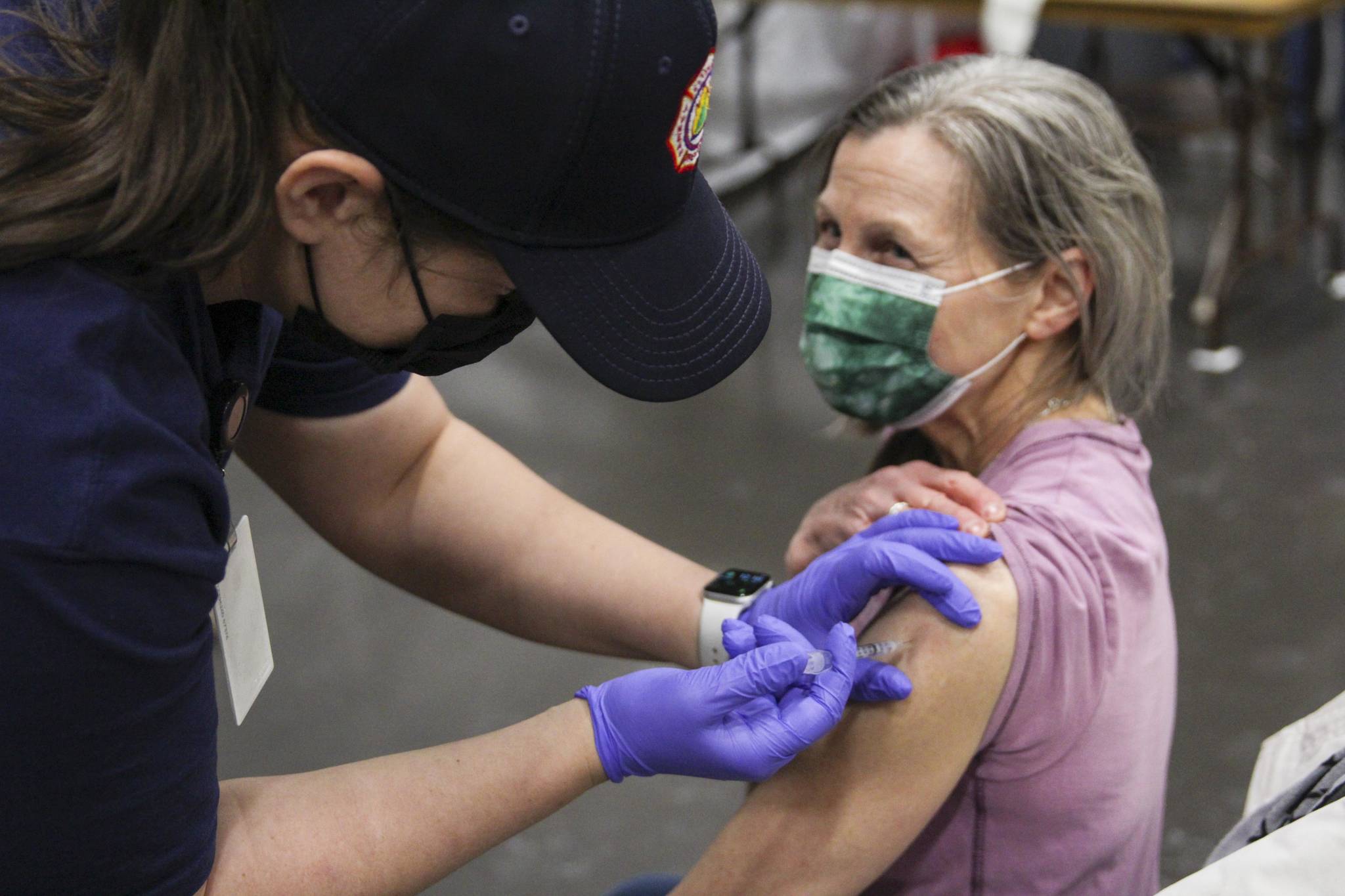 Wendy Wallers administers the coronavirus vaccine to Christina MacDougall during a clinic at Centennial Hall on Feb. 11, 2021. The City and Borough of Juneau lowered the risk level for the coronavirus to Level 1 on Feb. 17, the lowest since the system was put in place. (Michael S. Lockett / Juneau Empire)