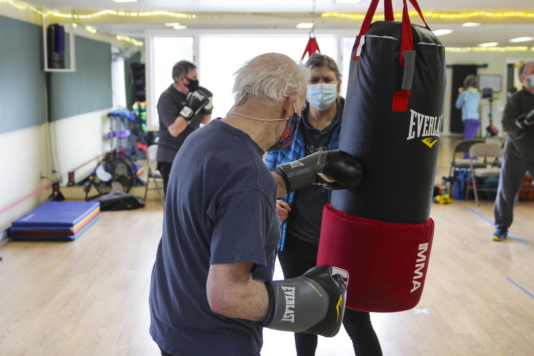 Steve Wolf strikes a punching bag as his wife Bev Ingram holds it during a boxing class designed to help fight back against the symptoms Parkinson’s disease through a specific regimen at Pavitt Health and Fitness on March. 2, 2021. (Michael S. Lockett / Juneau Empire)