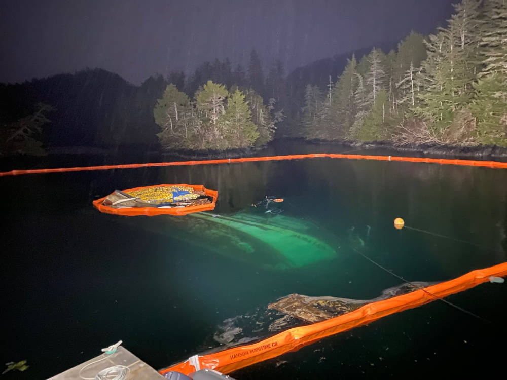 The submerged 52-foot fishing vessel, Haida Lady, surrounded by boom to contain leaking fuel, February 28, 2021. (Courtesy photo / U.S. Coast Guard)