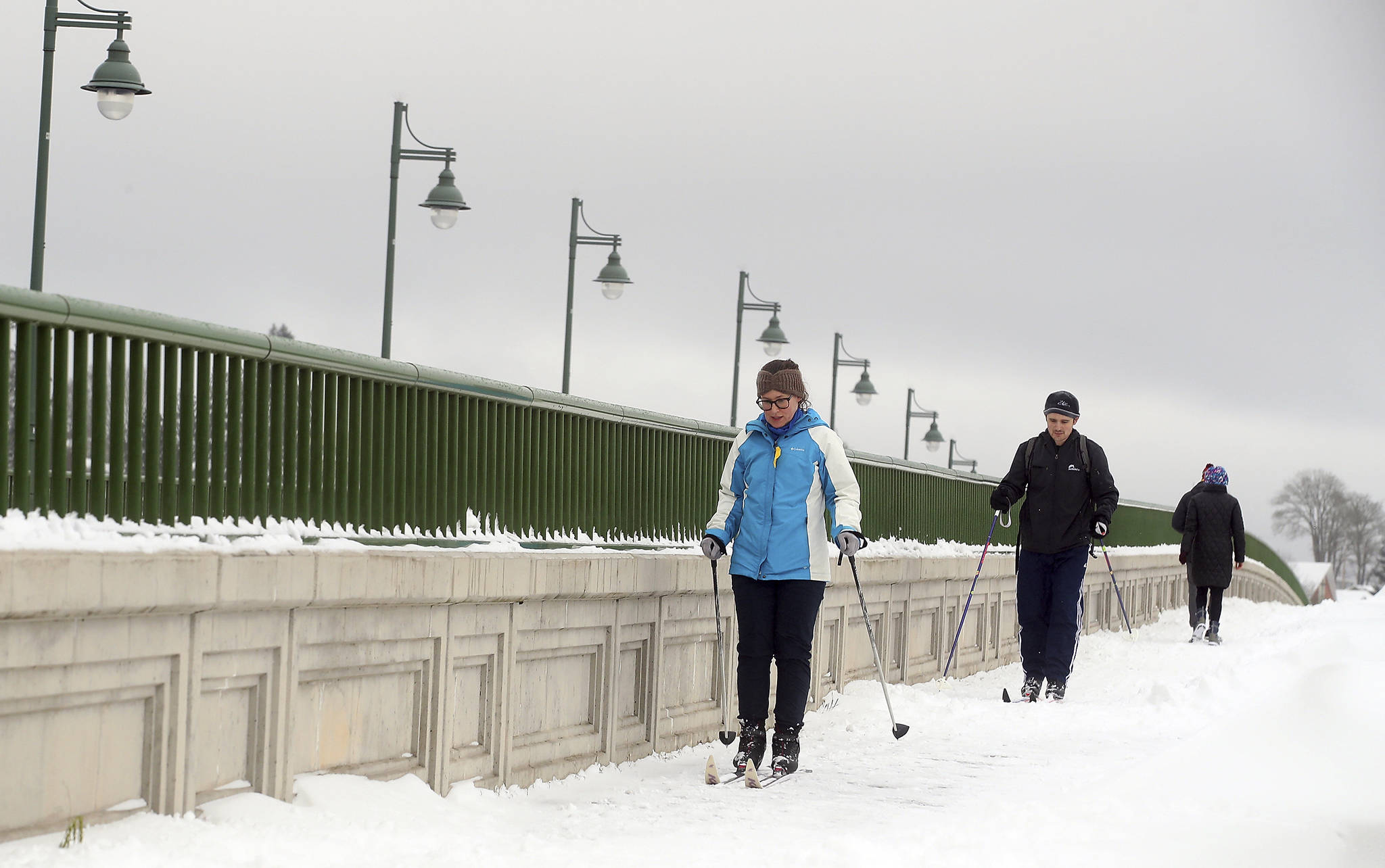 Erin Jaske and Scott Sandridge cross country ski across the Manette bridge in Bremerton, Wash., on a snowy day, in this Saturday, Feb. 13, 2021, file photo. During the pandemic, people around the world sought relief from lock downs and working from home in leisure sports. (Meegan M. Reid / Kitsap Sun)