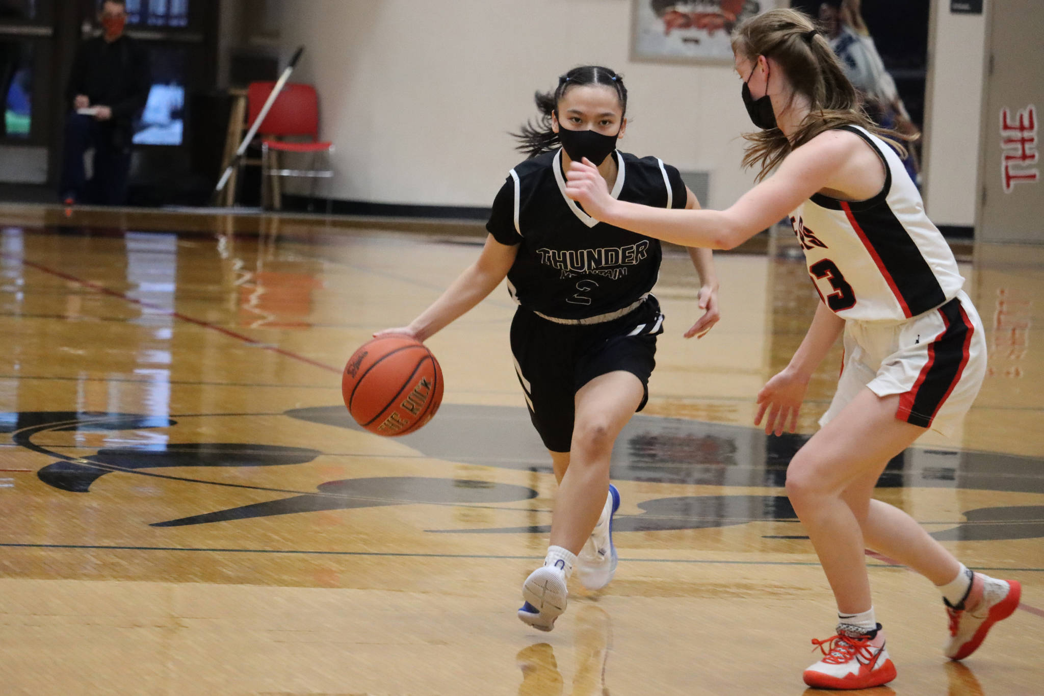 Thunder Mountain High Schools Mary Khaye Garcia (2) dribbles toward Juneau-Douglas High School: Yadaa.at Kalés Skylar Tuckwood (13) during a 46-41 TMHS victory. It took four quarters and two overtime periods to determine which team would go on to face Ketchikan High School in Ketchikan. (Ben Hohenstatt / Juneau Empire)