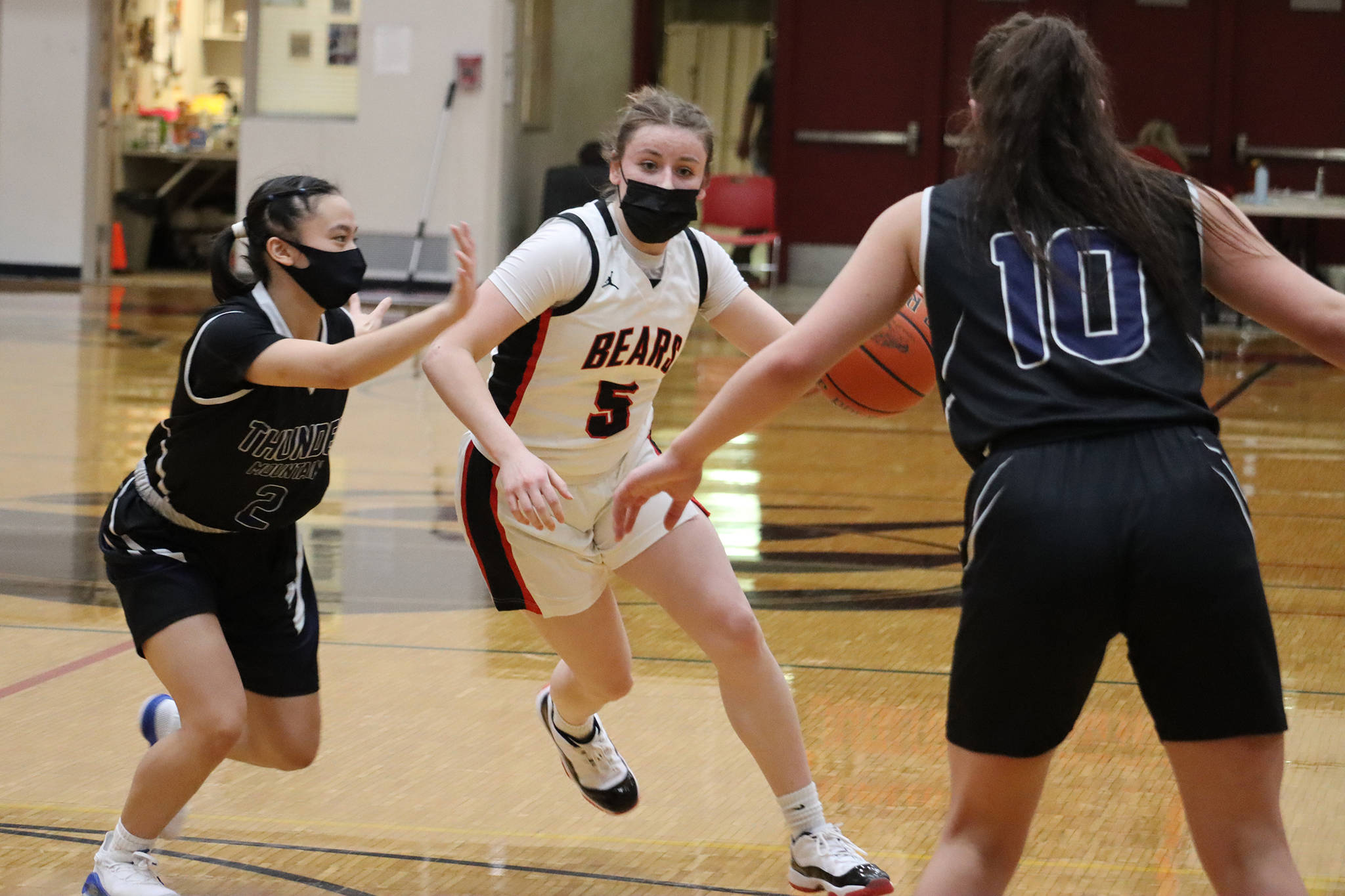 Juneau-Douglas High School: Yadaa.at Kalé’s Kiana Potter (5) drives toward the hoop while being defended by Thunder Mountain High School’s Mary Khaye Garcia (2) and Riley Traxler (10). Potter finished the game with 15 points and 16 rebounds. (Ben Hohenstatt / Juneau Empire)
