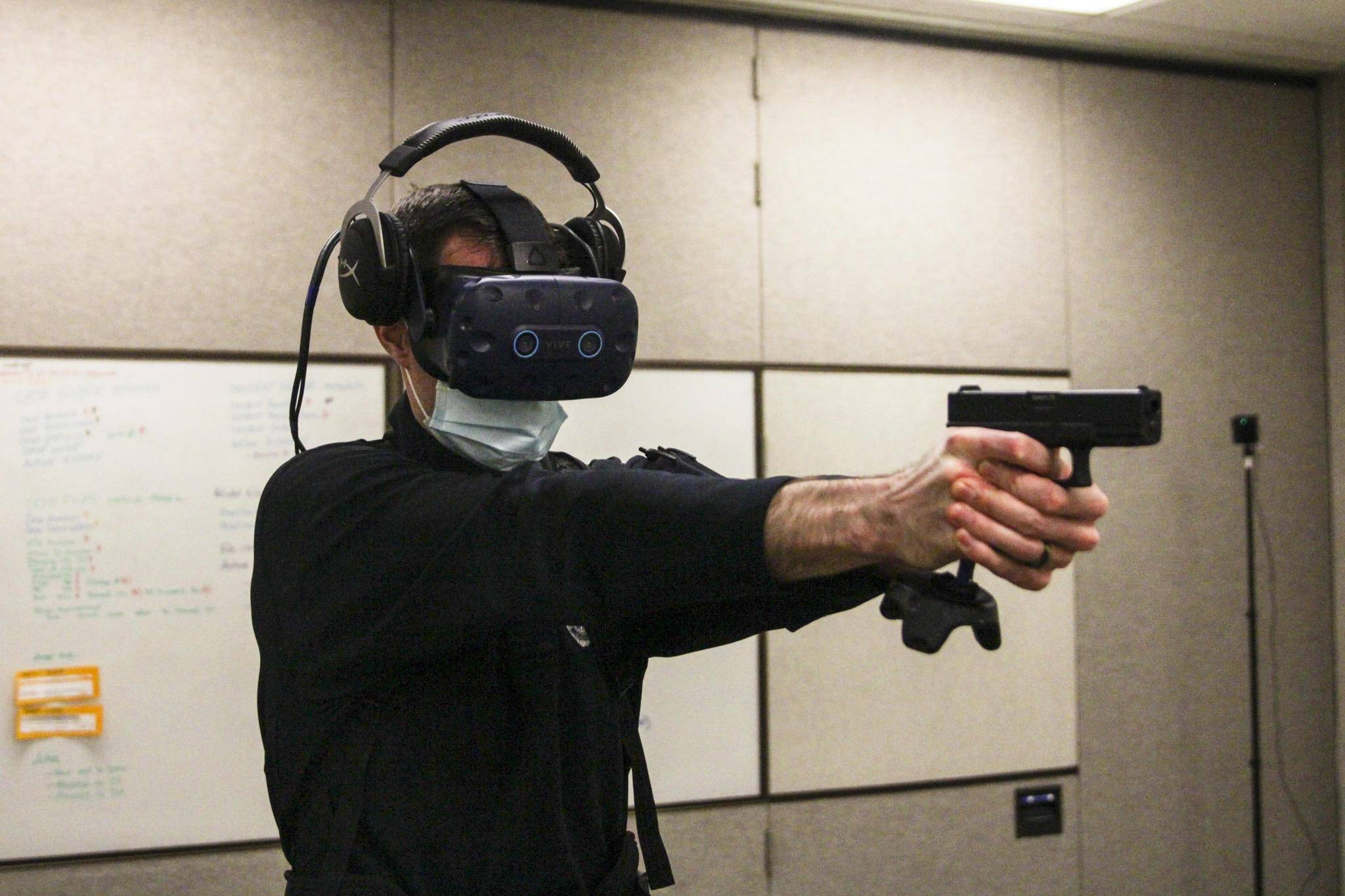 Detective Patrick Taylor draws a sidearm-controller during a VR training simulation on March 17, 2021 as Sgt. Sterling Salisbury controls the scenario from a computer elsewhere. (Michael S. Lockett / Juneau Empire)