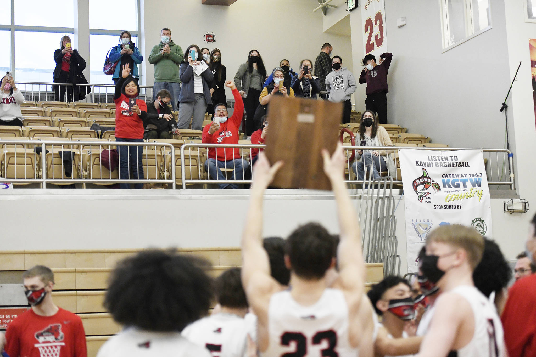 Juneau-Douglas High School: Yadaa.at Kalé player Cooper Kriegmont holds the 2021 Region V championship plaque up for Juneau spectators following a 87-68 win over Ketchikan in the boys’ varsity Region V basketball championship at Clarke Cochrane Gymnasium on Saturday, March 20, 2021. (Dustin Safranek / Ketchikan Daily News)