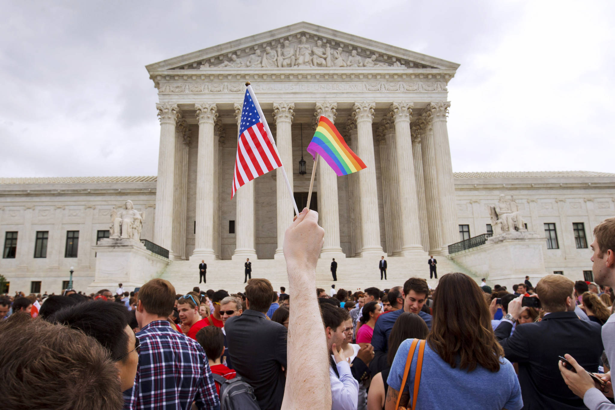 A man holds a U.S. and a rainbow flag outside the Supreme Court in Washington in 2015 after the court legalized gay marriage nationwide. Court documents show the state of Alaska for years maintains a discriminatory policy that denied some same-sex spouses benefits by wrongly claiming gay marriage was not recognized in Alaska, long after courts ordered they be recognized. (AP Photo / Jacquelyn Martin)