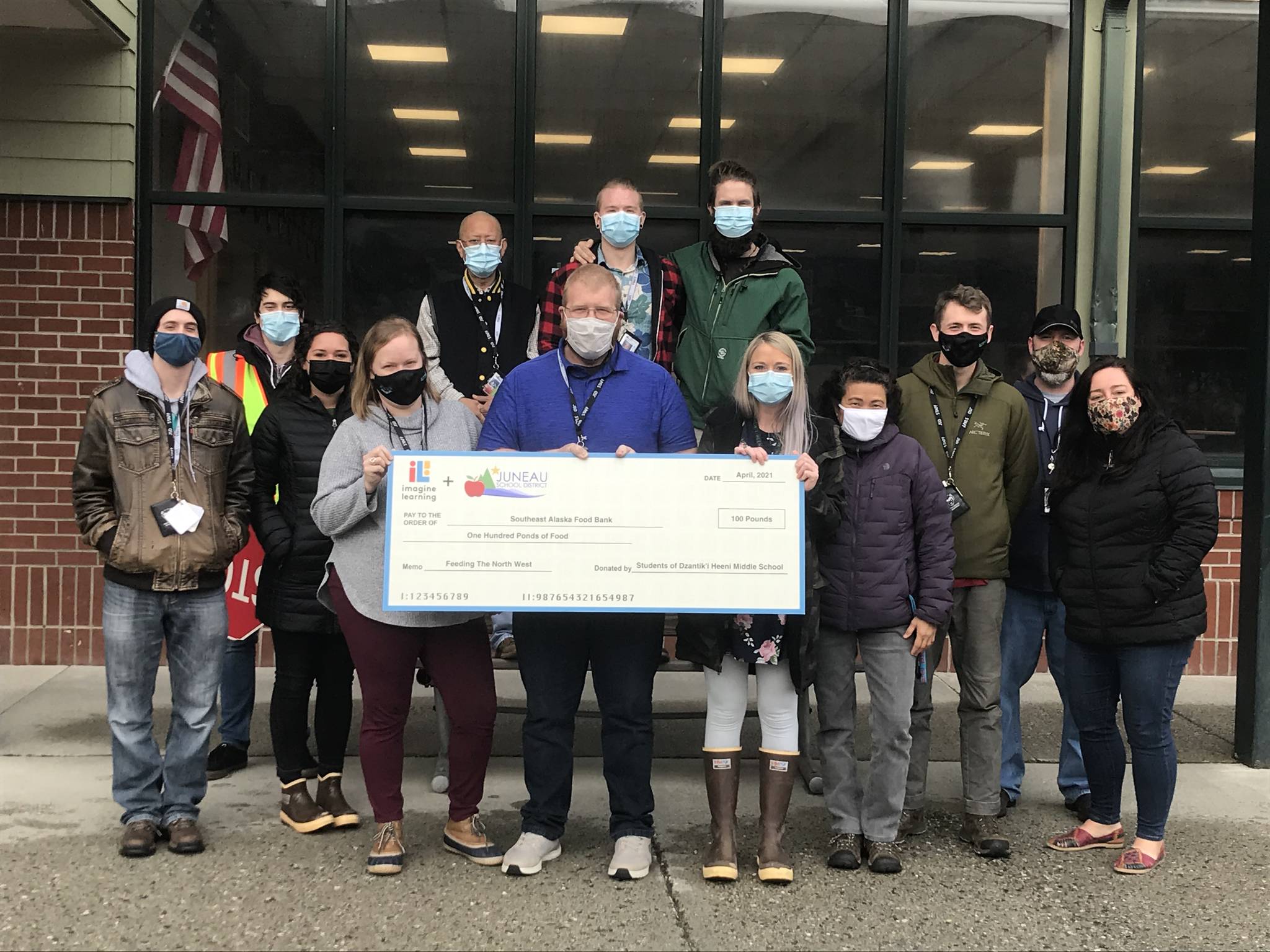 Courtesy photo / Imagine Learning 
Educators at Dzantik’i Heeni Middle School hold a giant check for the food donated to the Southeast Alaska Food Bank through a drive that math students at the school participated in.
