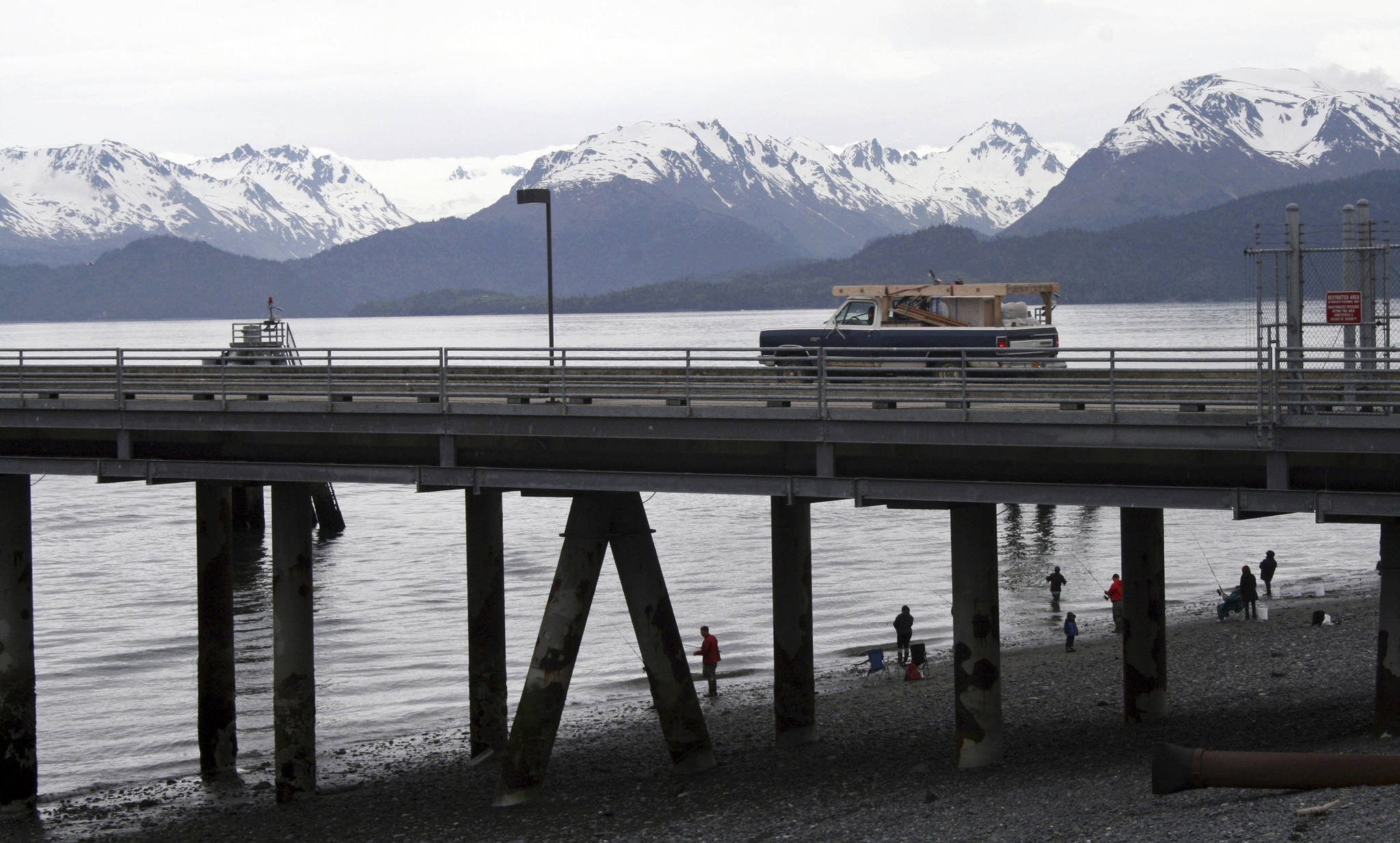 In this May 2015 photo, a vehicle drives on a pier to be loaded onto an Alaska state ferry while people fish underneath the pier in Homer, Alaska. The U.S. Supreme Court will hear oral arguments Monday, April 19, 2021, in a case that will determine who is eligible to receive more than $530 million in federal virus relief funding set aside for tribes more than a year ago. More than a dozen Native American tribes sued the U.S. Treasury Department to keep the money out of the hands of Alaska Native corporations, which provide services to Alaska Natives but do not have a government-to-government relationship with the United States. (AP Photo / Mark Thiessen)