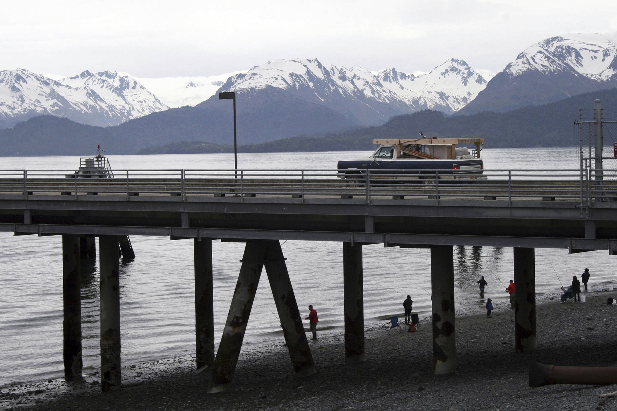 FILE - In this May 24, 2015, file photo, a vehicle drives on a pier to be loaded onto an Alaska state ferry while people fish underneath the pier in Homer, Alaska. The U.S. Supreme Court will hear oral arguments Monday, April 19, 2021, in a case that will determine who is eligible to receive more than $530 million in federal virus relief funding set aside for tribes more than a year ago. More than a dozen Native American tribes sued the U.S. Treasury Department to keep the money out of the hands of Alaska Native corporations, which provide services to Alaska Natives but do not have a government-to-government relationship with the United States. (AP Photo/Mark Thiessen, File)