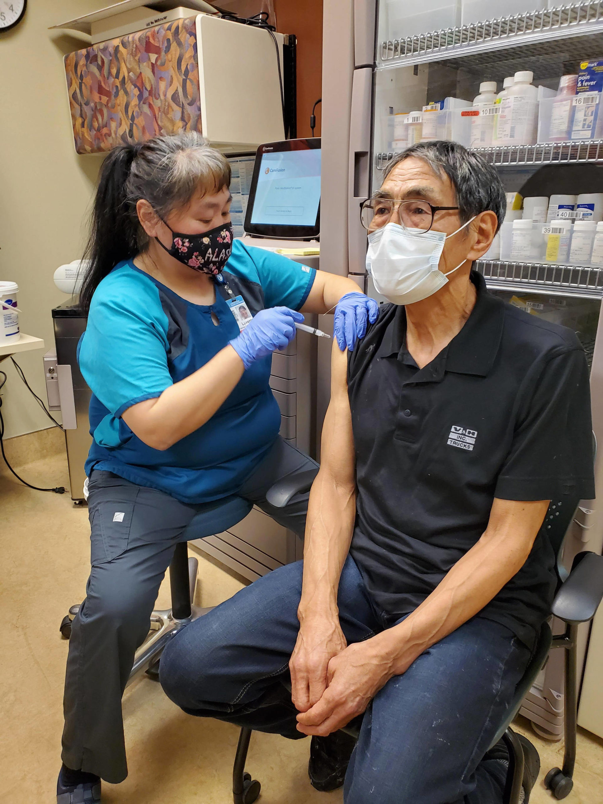 In this photo provided by Norton Sound Health Corp., is nurse LaVerne Saccheus providing a vaccination to Unalakleet elder Joseph “Nupid” Katchatag in Unalakleet, Alaska, on Dec. 23, 2020. Alaska’s highest vaccination rates among those 16 or older have been in some of its remotest, hardest-to-access communities, where the toll of past flu or tuberculosis outbreaks hasn’t been forgotten. (Carol Charles / Norton Sound Health Corp.)