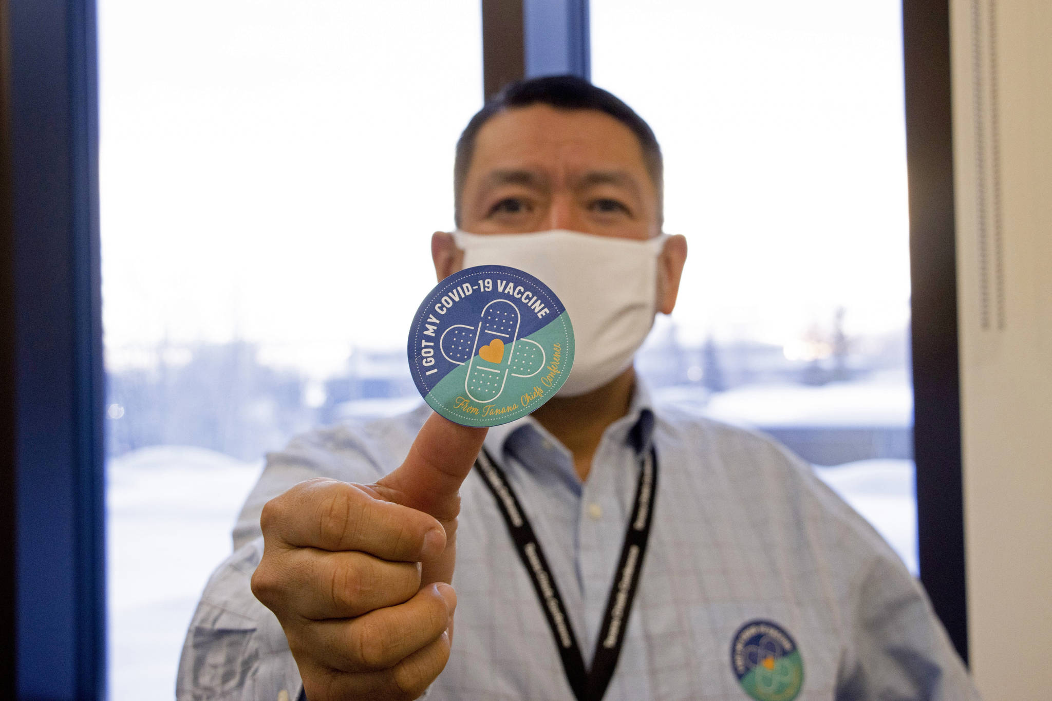 In this undated photo provided by the Tanana Chiefs Conference, shows PJ Simon, chief and chairman of the conference, from Fairbanks, Alaska, displaying a COVID-19 vaccination sticker. Alaska has been one of the leading states in the percentage of its population to be vaccinated against COVID-19. But some of Alaska’s highest vaccination rates have been in some of its most remote, hardest-to-access communities, where the toll of past flu or tuberculosis outbreaks hasn’t been forgotten. (Rachel Saylor / Tanana Chiefs Conference)