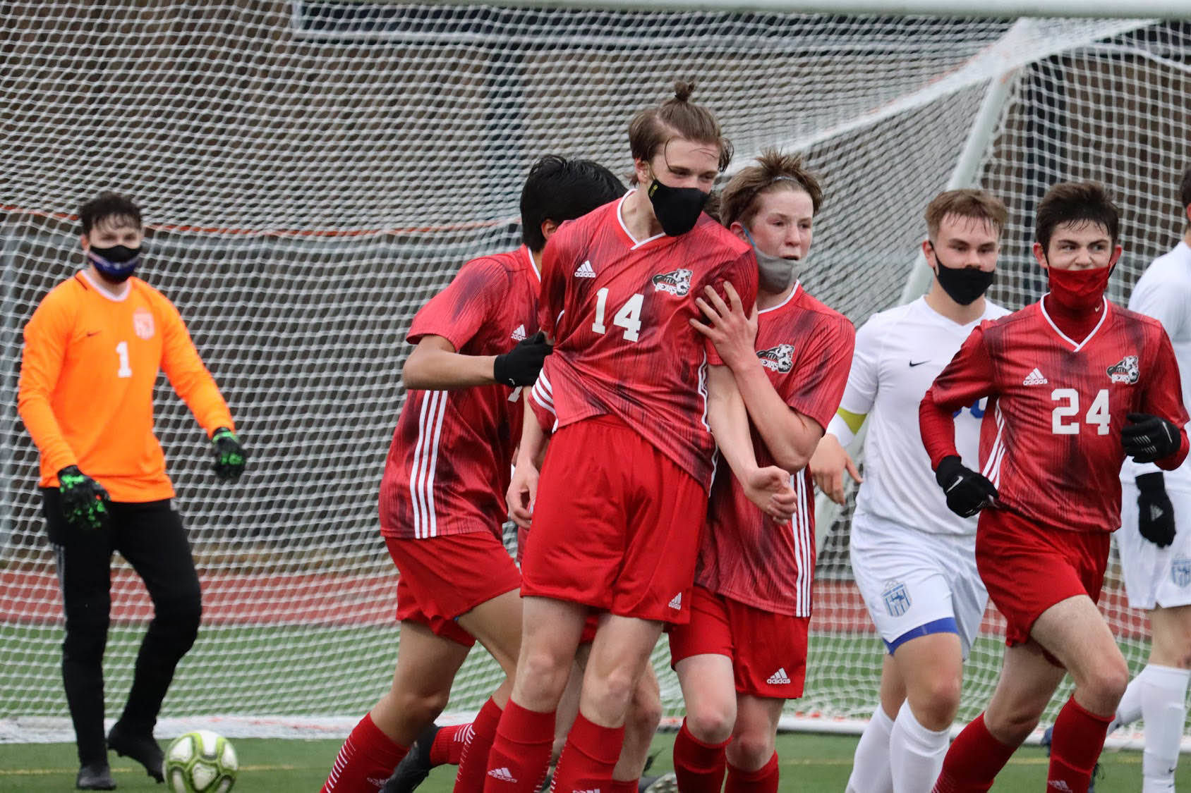 Members of the JDHS boys soccer team help junior Callan Smith celebrate a goal in the season opener against TMHS Tuesday night. In the end, TMHS walked away with a 3-2 victory. (Ben Hohenstatt/Juneau Empire)