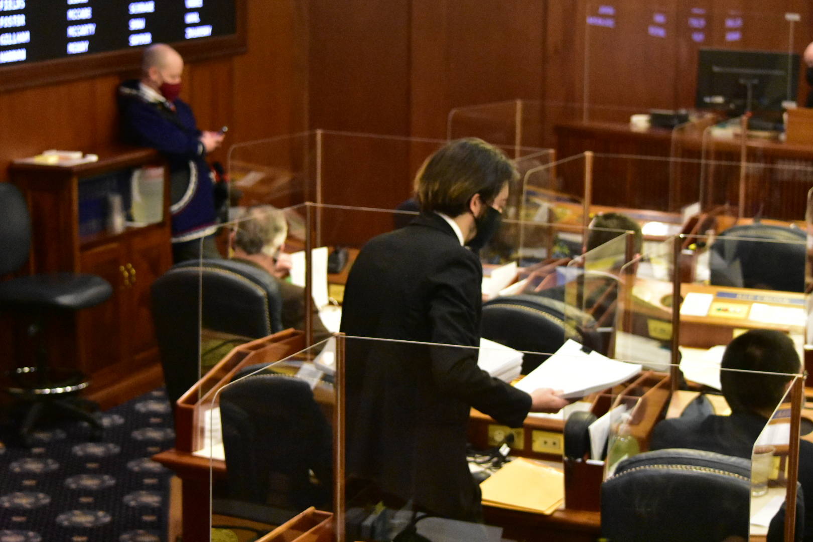 A page in the Alaska House of Representatives hands out copies of a budget bill over 100 pages long on Friday, April 30, 2021. (Peter Segall / Juneau Empire