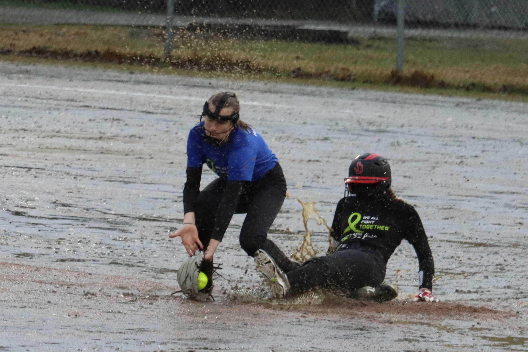 JDHS’ Gloria Bixby slides safe into second base and under the tag of TMHS’ Jenna Dobson during the first inning of a drizzly Friday night game against Thunder Mountain High School. JDHS leaped out to a 7-0 lead in the first inning and wound up winning 15-0. (Ben Hohenstatt / Juneau Empire)