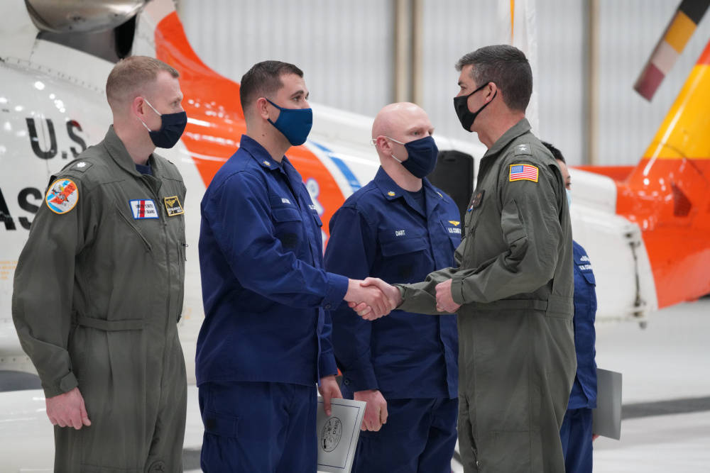 Rear Adm. Nathan A. Moore, commander, Coast Guard 17th District, shakes hands with a member at Air Station Sitka after presenting the crew with Air Medals, May 7, 2021. The aircrew received medals in recognition of the heroic actions and extraordinary measures taken to save the life of a lone fisherman adrift at sea Nov. 1, 2020. (U.S. Coast Guard photo)