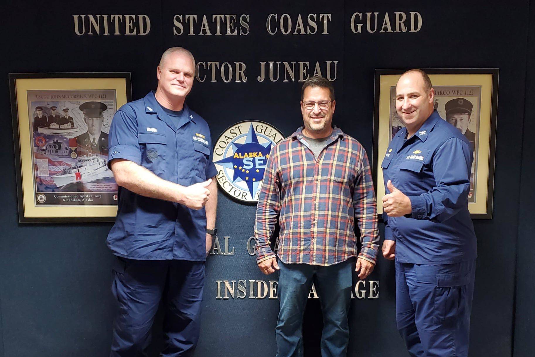 Incoming Coast Guard Sector Juneau commander Capt. Darwin A. Jensen, left, and outgoing commander Capt. Stephen R. White, right, congratulate Herman Cestero, center, for his quick action in rescuing a fisherman in distress on June 24, 2021. (Michael S. Lockett / Juneau Empire)