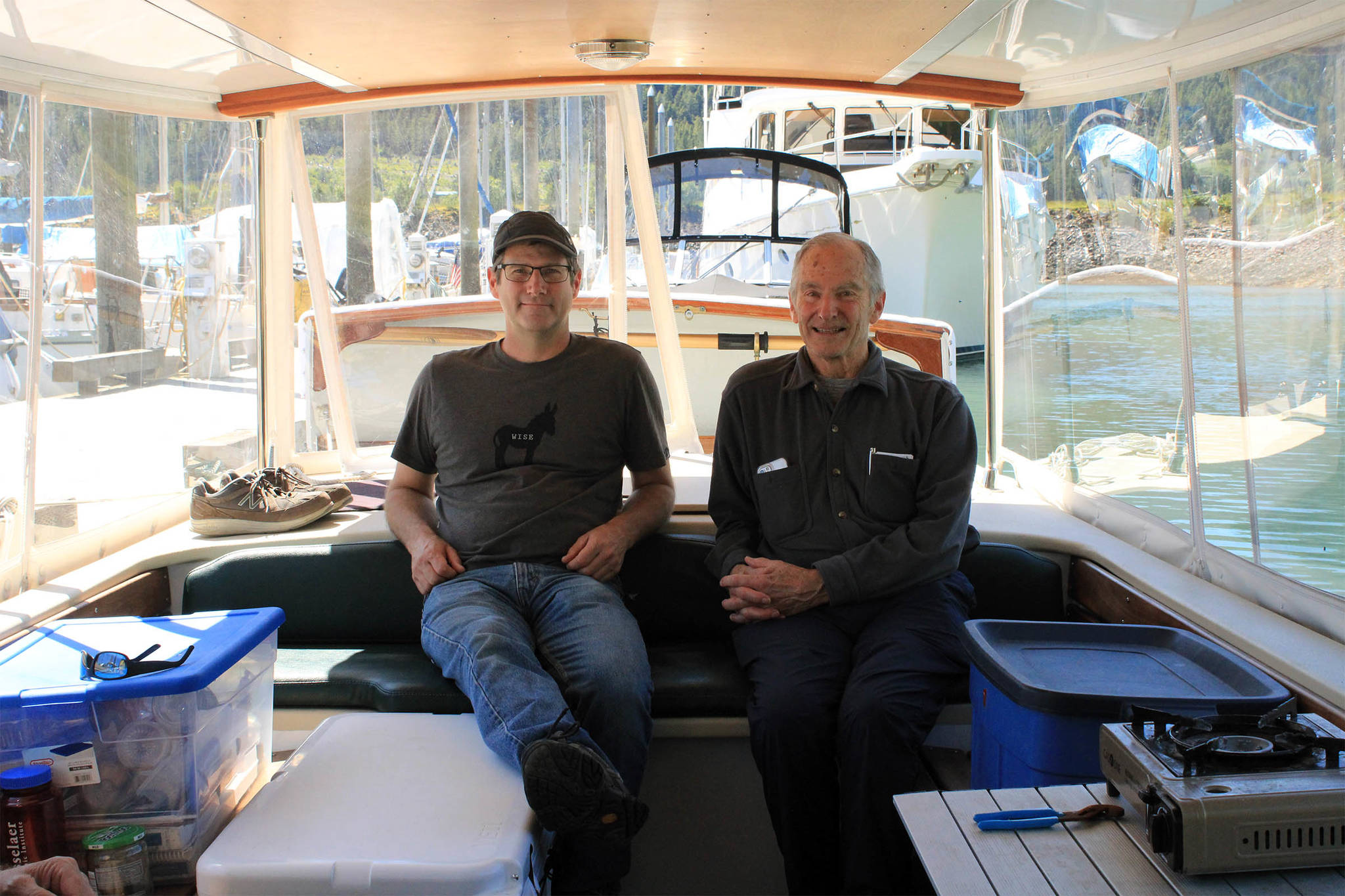 Alex Borton, left, and his father David Borton relax in the Wayward Sun, a solar-powered vessel designed by their company, Solar Sal Boats. The pair stopped in Juneau Sunday, June 27 as part of their quest to traverse Alaska’s Inside Passage in a solar-powered vessel. (Dana Zigmund/Juneau Empire)