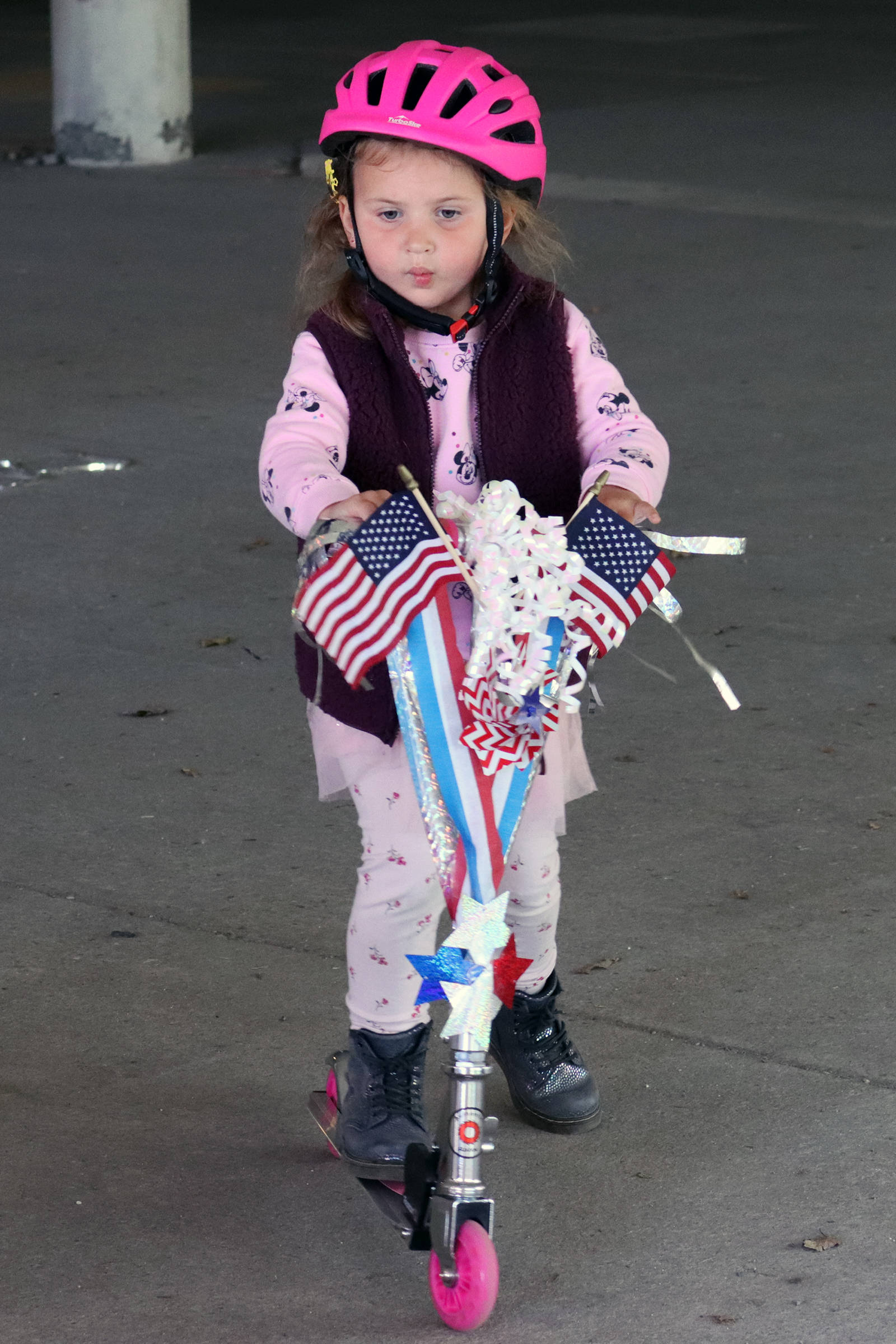 Clara Malueg, 4, scoots around the Douglas Public Library parking garage on Saturday, July 3. While most parents and youths decorated bikes, Mauleg and mom Amy Balagna gave a scooter patriotic flair. (Ben Hohenstatt / Juneau Empire)