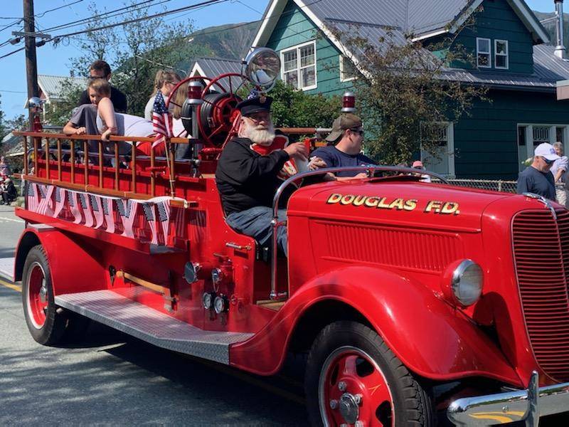 An antique fire truck makes its way along the Douglas parade route on Sunday, July 4, 2021. (Dana Zigmund / Juneau Empire)