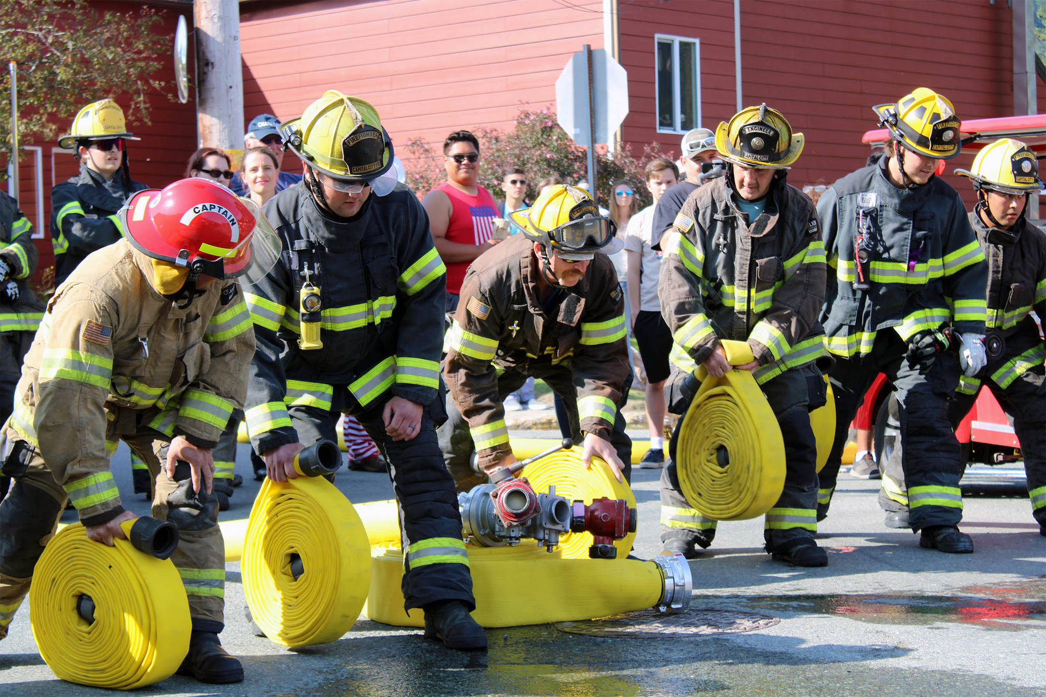 Members of Capital City Fire and Rescue competed in the “Olde Time Fireman’s Hose Race” as hundreds cheered the different crews in their efforts to quickly unroll and connect the hose to water in front of the Volunteer Fire House. (Dana Zigmund/Juneau Empire)