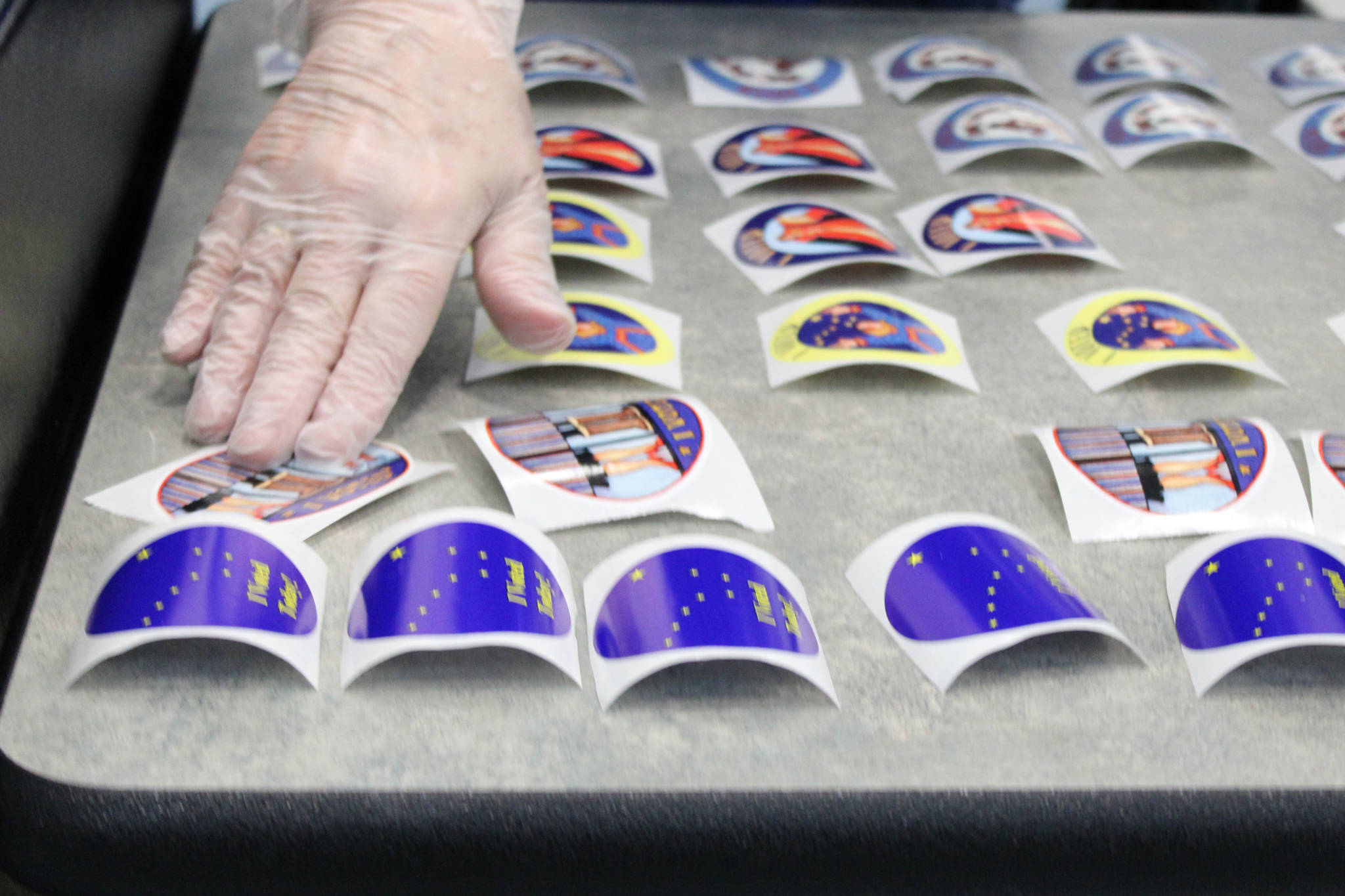 An election official lays out more I voted stickers on Tuesday, Nov. 3. Stickers for the 2020 general election featured designs by Alaskan artist Barbara Lavallee. Election officials in Juneau said the sticker depicting a pair of Neoprene boots ha been particularly popular. (Ben Hohenstatt / Juneau Empire)