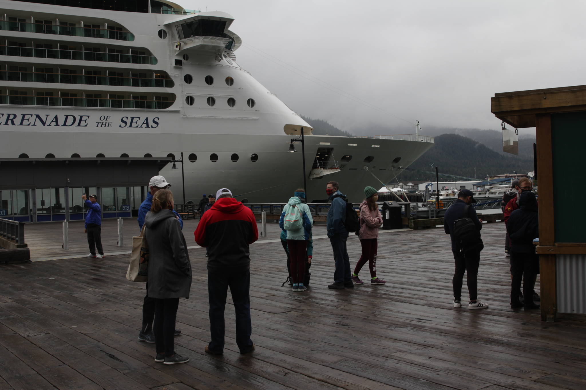 Tourists congregate in front of the Serenade of the Seas, seen here moored downtown, on Friday morning. The Royal Caribbean cruise ship is the first large cruise ship to come to Juneau since the pandemic caused the cancellation of the 2020 cruise ship season and delayed the 2021 season. (Michael S. Lockett / Juneau Empire)