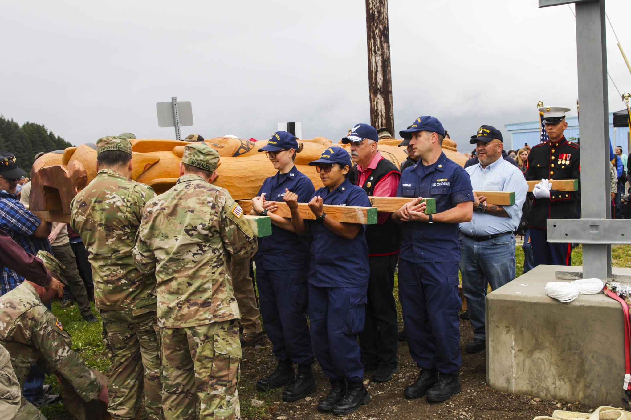 Veterans and active duty servicemembers, including Coast Guardsmen from Coast Guard Sector Juneau, carry a totem pole honoring veterans into place in Hoonah on July 24, 2021. (Michael S. Lockett / Juneau Empire)