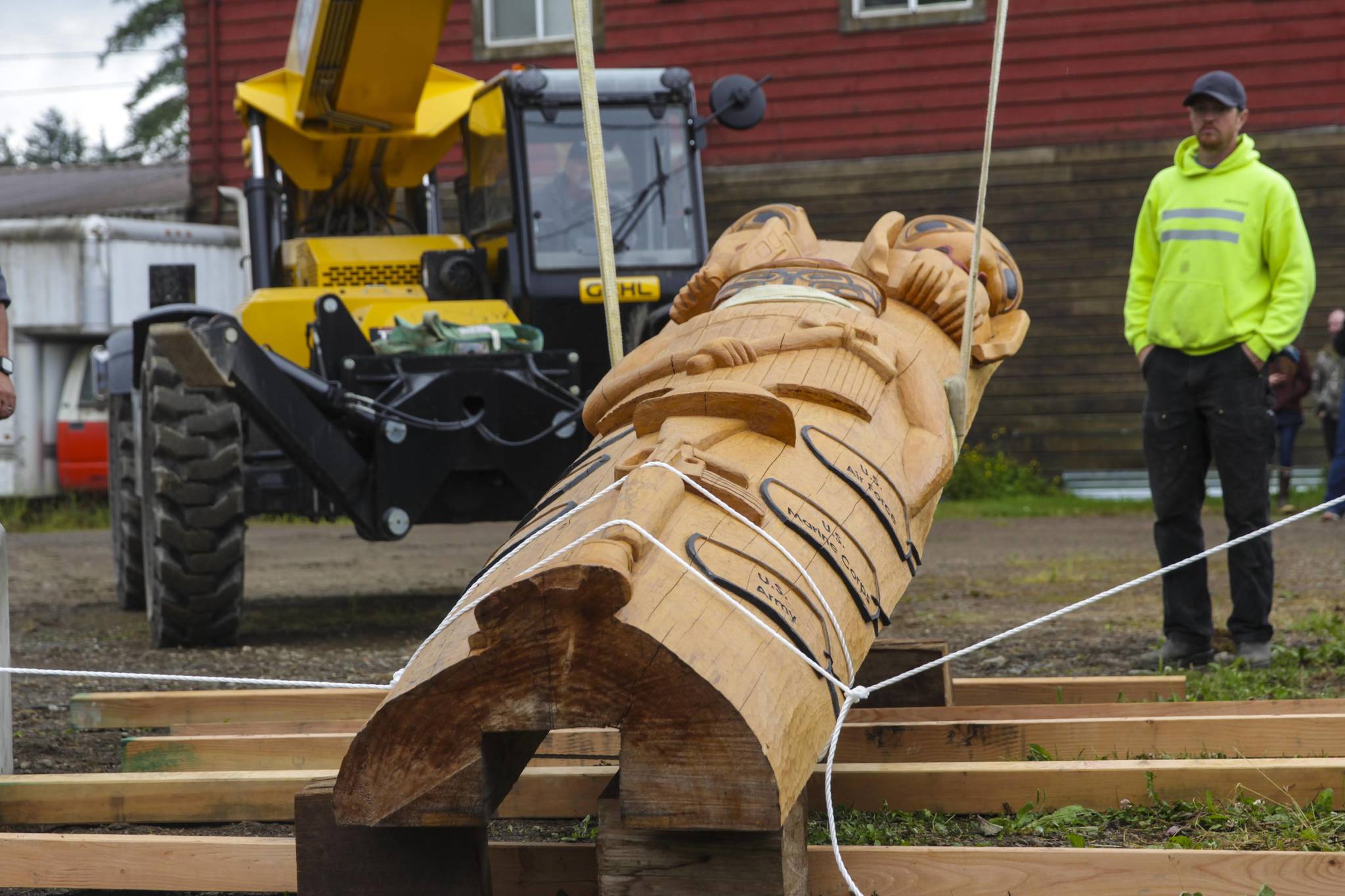 Contractors from Dawson Construction raise a totem pole honoring veterans of the armed services into place in Hoonah on July 24, 2021, in a ceremony attended by hundreds. (Michael S. Lockett / Juneau Empire)