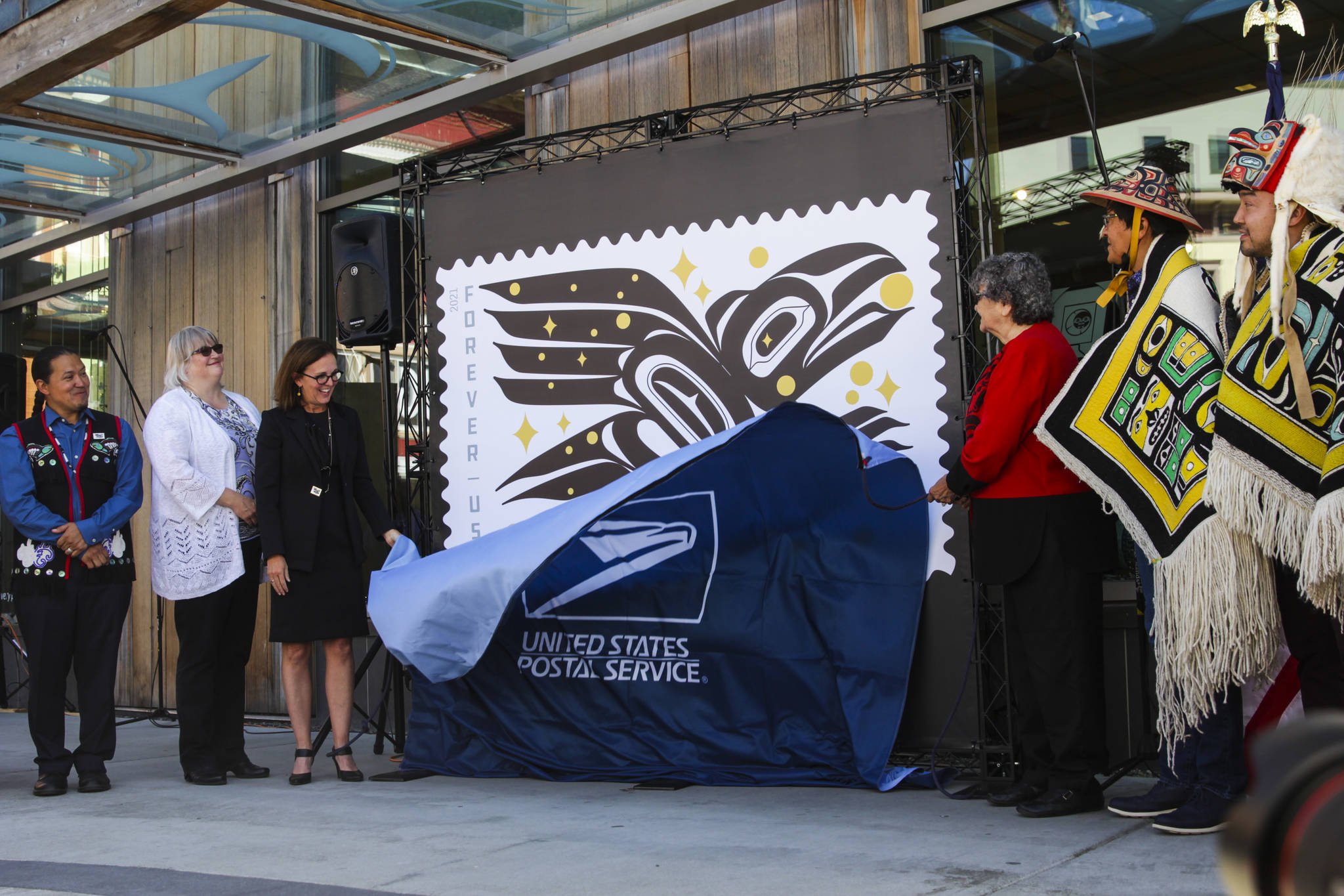 Michael S. Lockett / Juneau Empire
Officials, artists and key Southeast Alaska figures alongside U.S. Postal Service leadership unveil the Raven Story stamp as part of the official release ceremony in front of the Sealaska Heritage Institute’s Walter Soboleff Building on Friday, July 30, 2021.