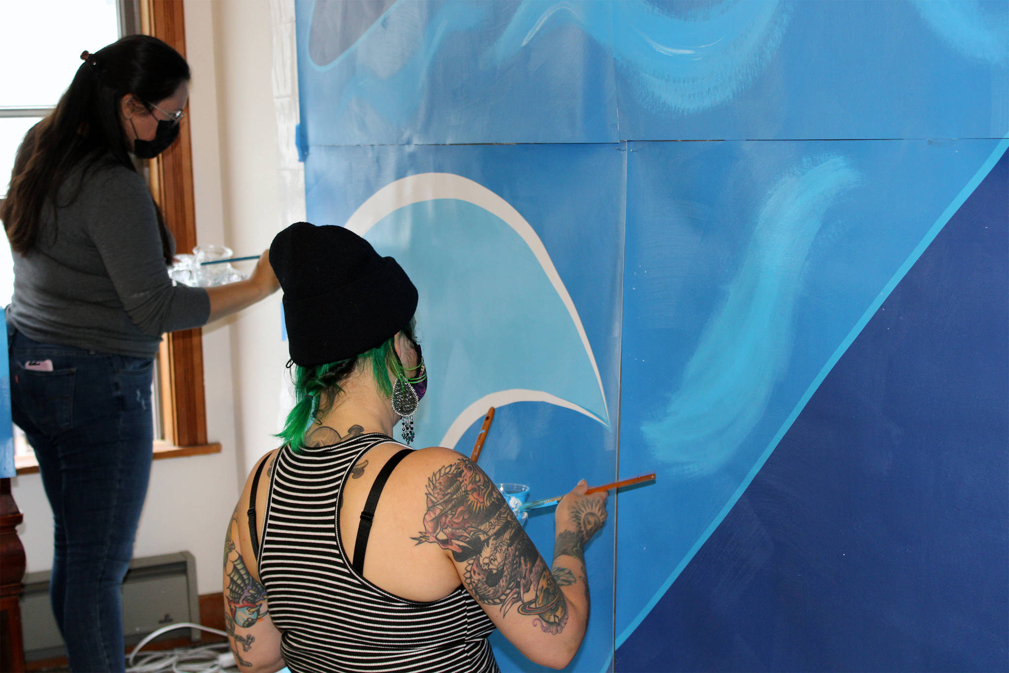 Dana Zigmund / Capital City Weekly 
Shara Kay Diamond, left, of Anchorage and Chelsea Bighorn, right, of Sante Fe, apply paint to a section of a mural that will depict Elizabeth Kaaxgal.aat Peratrovich, a Tlingit civil rights icon. The mural is the work of Tlingit and Athabascan artist, designer, and activist Crystal Kaakeeyaa Worl. Kay Diamond and Bighorn are apprentices on the project. Right, local artist Crystal Kaakeeyaa Worl, center, and her apprentices, Shara Kay Diamond, left, and Chelsea Bighorn, right, assemble sections of the mural to apply paint in Worl’s downtown studio on Aug. 10.