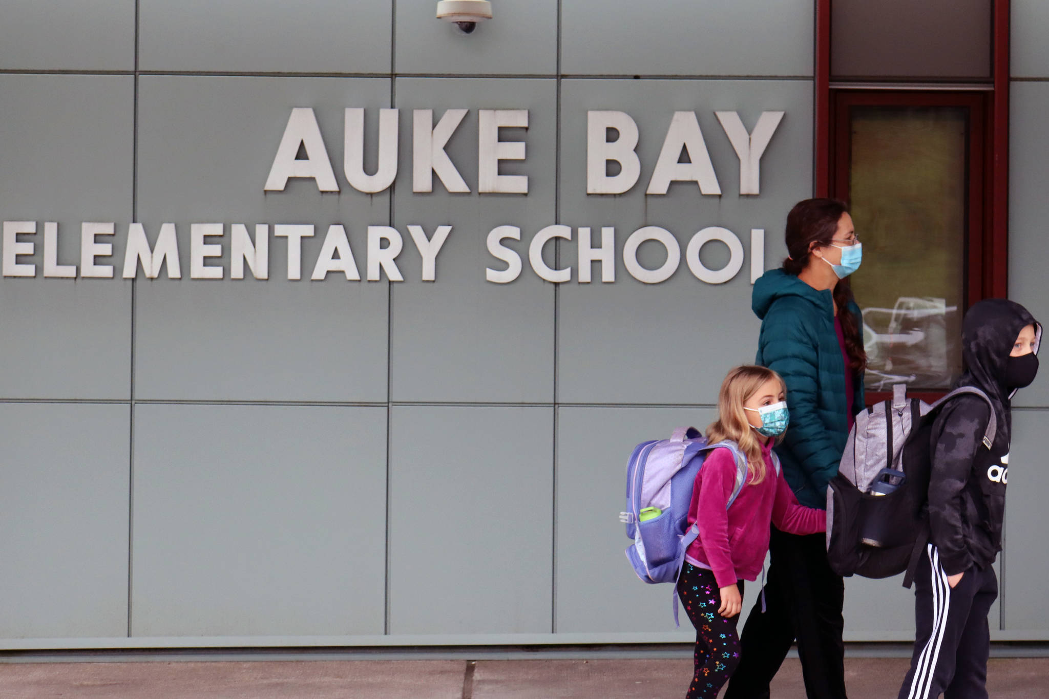 Kalei Shotwell walks third grade student Loche Hanselman and first grade student Ady Hanselman into Auke Bay Elementary School on Monday morning. Shotwell said she was both excited and nervous about the return of in-person, five-days-a-week school. Shotwell said she is impressed with Juneau School District’s mitigation policies. “I give the school a lot of credit,” Shotwell said. “It feels normal, and I think that’s a big deal for most people.” (Ben Hohenstatt/Juneau Empire)