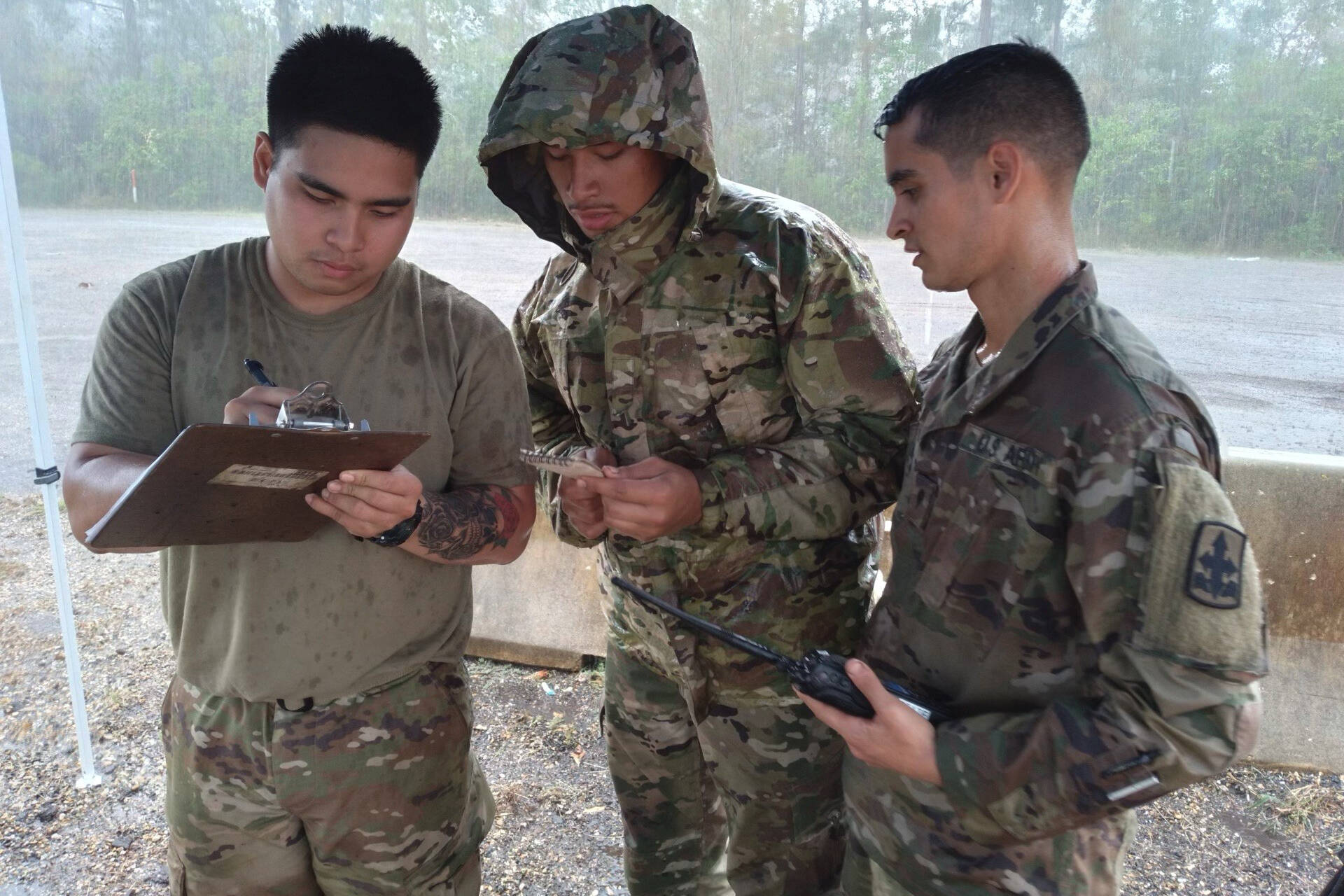 Sgt. Joemicheal Cristobal, Spc. Osias Passi, and Spc. Brennon Westfall, members of the Alaska Army National Guard and Task Force-Alaska, log trailer and driver information on a yard dog sheet, at a transportation yard in Roseland, Louisiana, Sept. 7, 2021. (U.S. Army National Guard / Staff Sgt. Jacob Tyrrell)