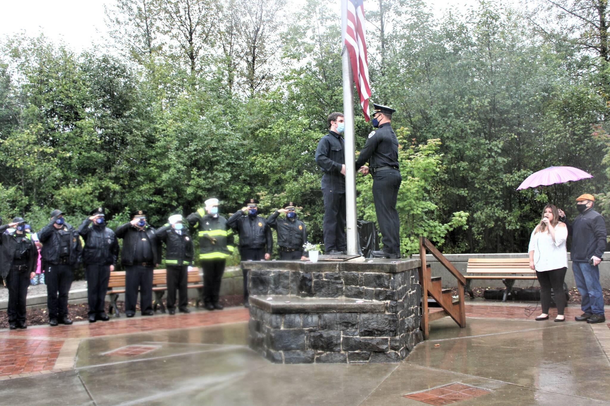 Under heavy rain and low clouds overhead, a few hundred people gathered in Riverside Rotary Park Saturday morning for solemn remembrance and honor the 20th anniversary of the 9/11 terrorist attacks. To honor the fall of the first tower at 9:59 a.m., officers quickly raised an American flag and then lowered it to half-mast while Alyssa Fischer sang the National Anthem. (Dana Zigmund/Juneau Empire)