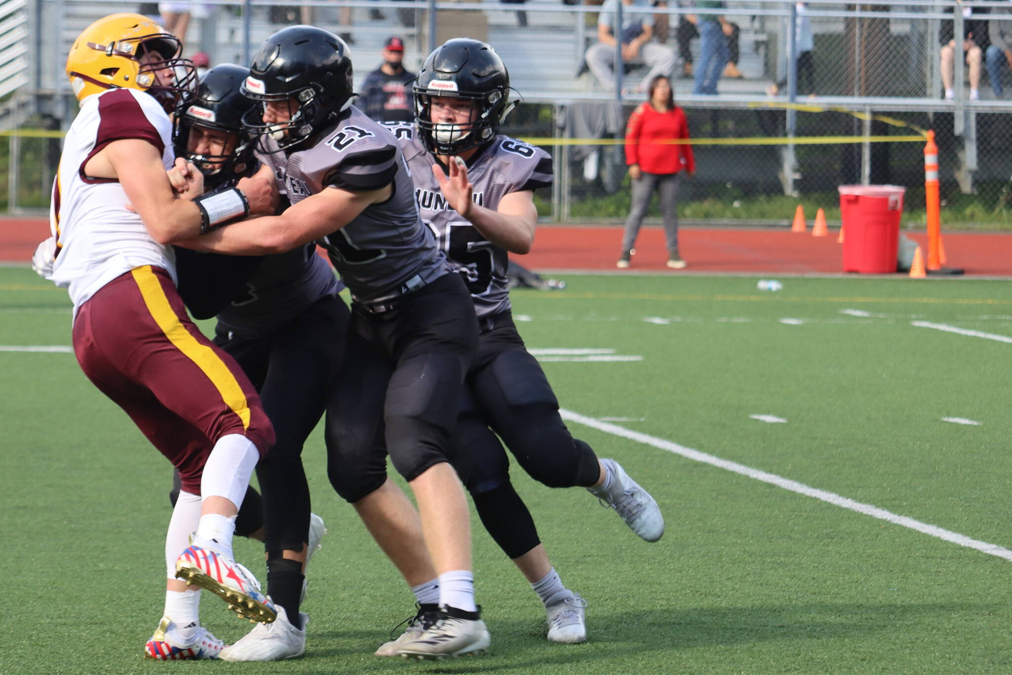 Lucas White (21) and two other Huskies take down a player from Dimond High School on Saturday, Aug. 21. Juneau coach Rich Sjoroos said solid tackling by White and others played a major role in the Huskies 27-14 win against Bartlett High School. (Ben Hohenstatt / Juneau Empire File)