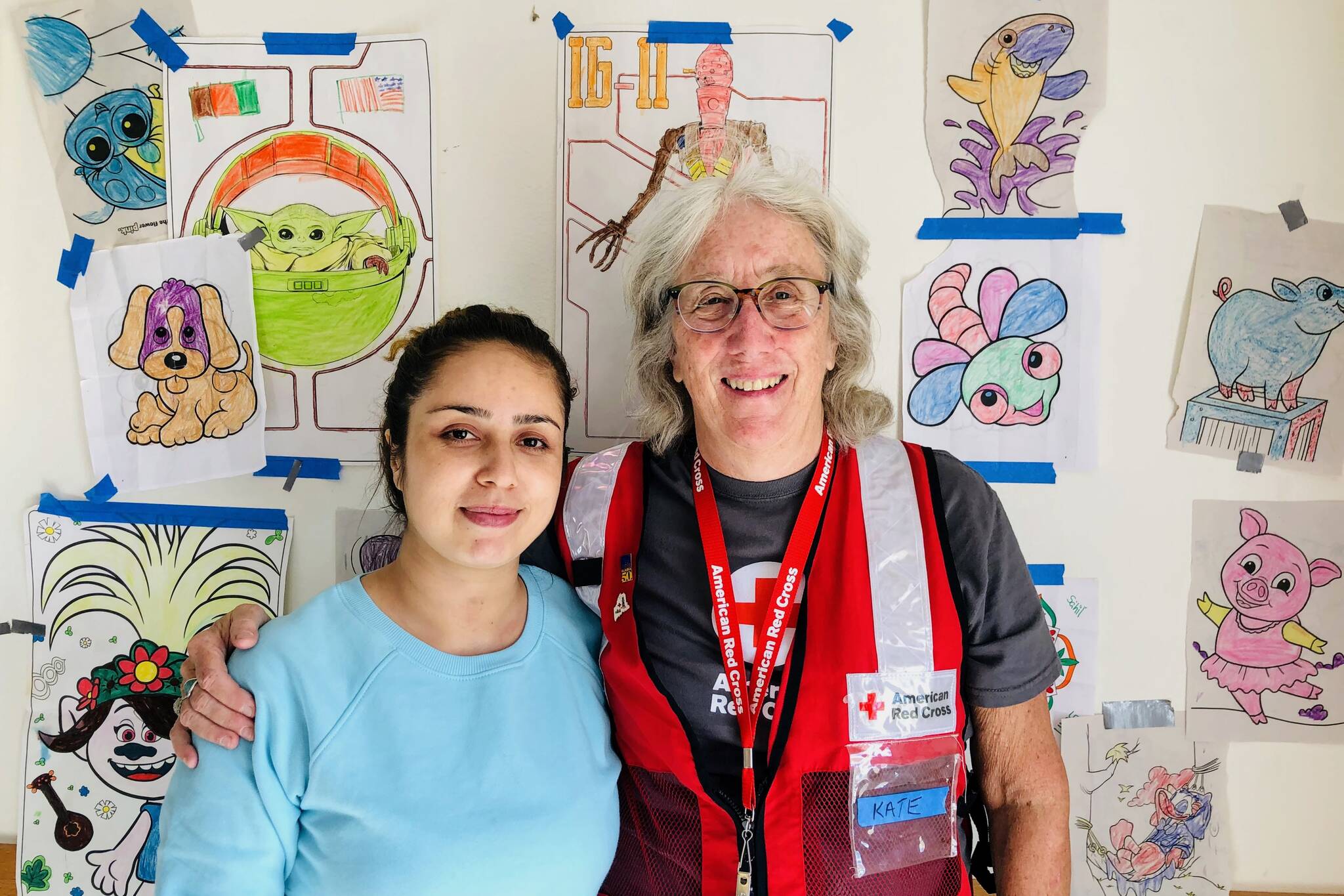 Kate Troll, right, and Yalda Battori, stand in front of pictures colored by refugee children from Afghanistan at Fort McCoy in Wisconsin. Troll recently returned from a two week deployment with the American Red Cross at McCoy, where nearly 13,000 Afghans are awaiting resettlement in the U.S. (Courtesy photo / Kate Troll)