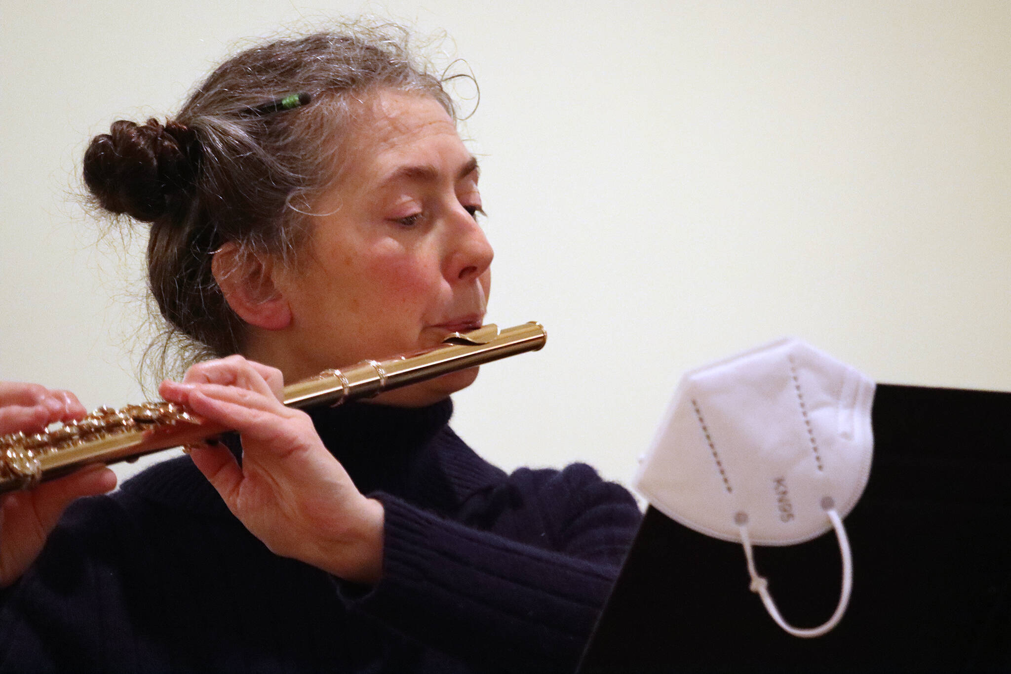 A face mask hangs off the corner of a music stand while Kathryn Kurtz rehearses ahead of the Juneau Symphony’s upcoming performance. The return to in-person shows means attendees will need to share proof of vaccination. (Ben Hohenstatt / Juneau Empire)