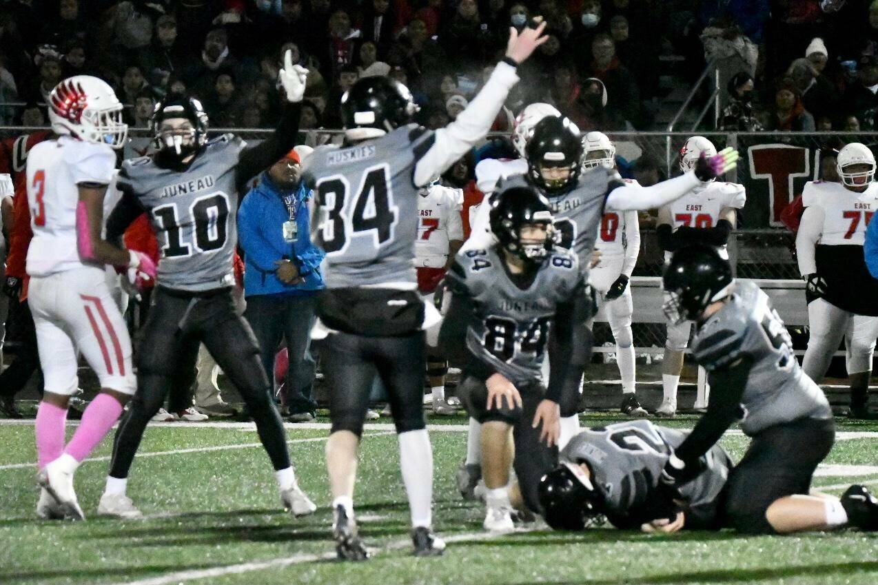 Huskies signal that they’ve got the ball as Lucas White (21), a junior, recovers a fumble. (Courtesy Photo / Larry Schrader)