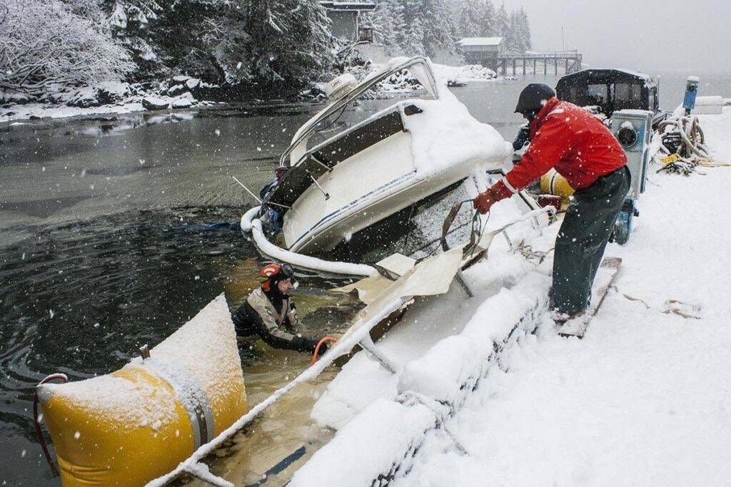Divers work to right a vessel capsized by snow in Don D. Statter Harbor in 2020. The Coast Guard and city both recently issued reminders to prepare for winter weather in the coming months. (Michael S. Lockett / Juneau Empire)