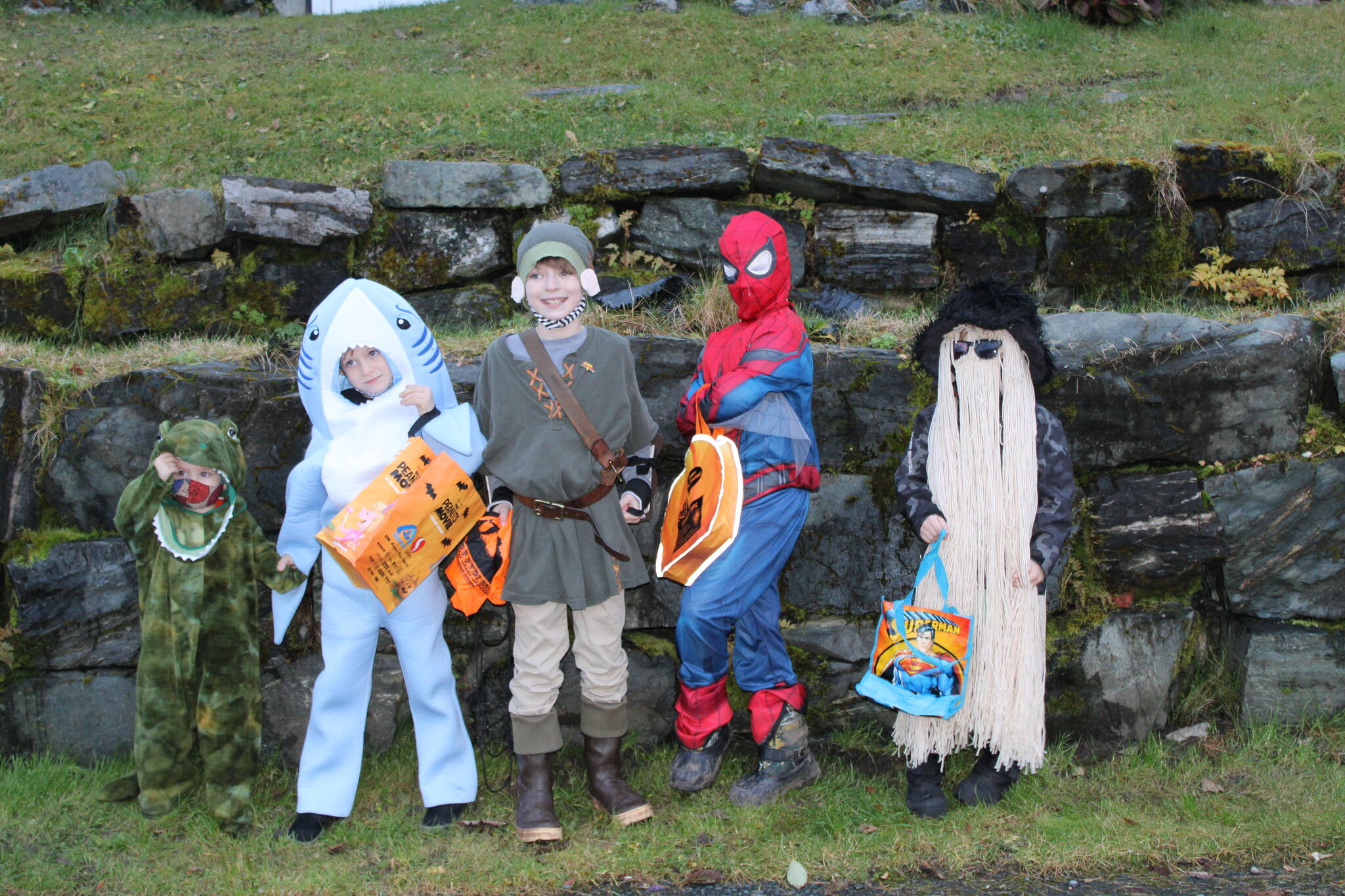 A dinosaur, a shark, an adventurer, Spider-Man, and Cousin It, gather on 5th Street in Douglas before heading down to the drive-through trick or treat event sponsored by the Douglas Fourth of July Committee on Saturday, Oct. 30. (Dana Zigmund/Juneau Empire)