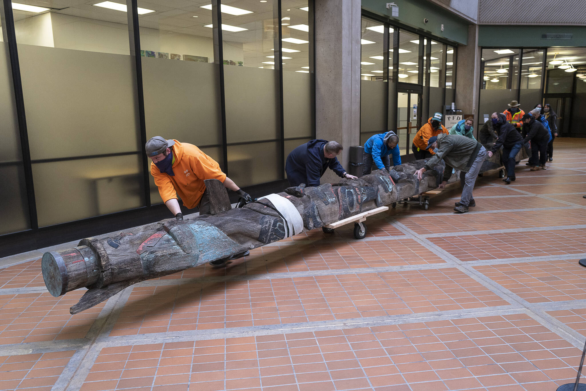 Workers move the Wooshkeetaan Kootéeyaa (totem pole) through the state office building on Oct. 15. After a few weeks of laying flat so that it can adjust to the climate inside the building, the totem pole will be raised and a celebration will be planned. (Michael Penn / For the Jundeau-Douglas City Museum)