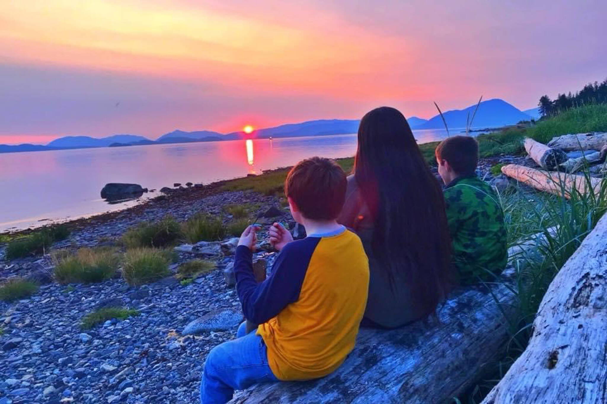 Yeilk’ Vivian Mork sits watching a sunset with nephews Timothy and Jackson Person, Wrangell. (Vivian Faith Prescott / For the Capital City Weekly)