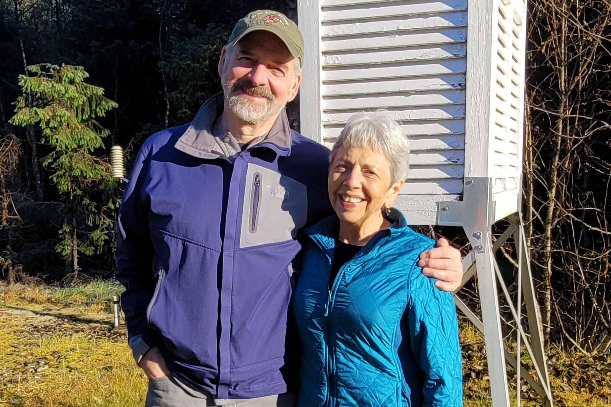 Jim Wild, left, and Mary Jo Lord-Wild, right, stand outside a weather collection station similar to one they have at their home in Elfin Cove. Lord-Wild recently received the Thomas Jefferson Award for her volunteer work collecting weather data over the last 47 years. (Courtesy photo/Kimberly Vaughan)