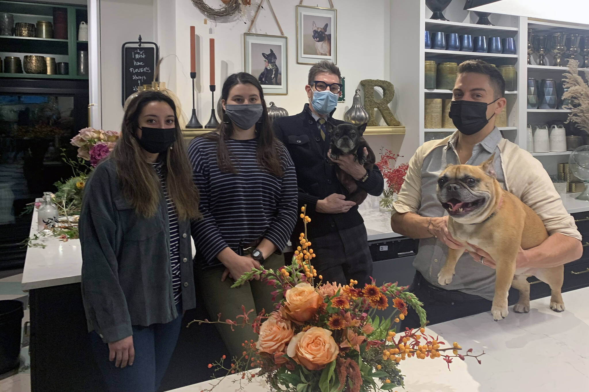 The staff at Frenchie's Floral Studio downtown takes a break from preparing Thanksgiving arrangements on Friday, Nov. 12. Florist Heather Alducin, (left), floral designer, Nikki Box, (second left), stand with shop owners Jeremy Bauer, (center right), and Jason Clifton, (right). French bulldogs George (held by Bauer) and Gracie (on table), served as the inspiration for the shop's name. (Dana Zigmund/Juneau Empire)