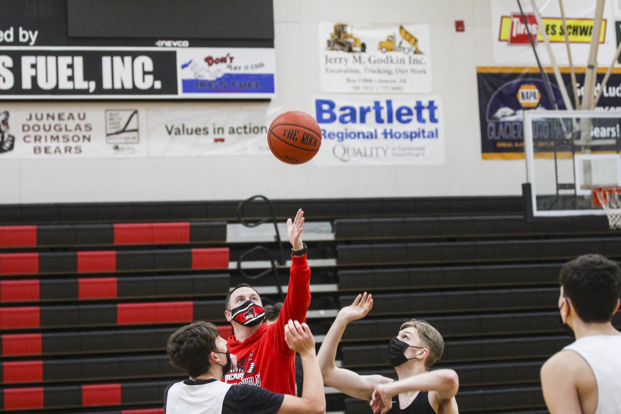 Juneau-Douglas High School: Yadaa.at Kalé varsity boys basketball players Orion Dybdahl, left and Jake Sleppy, right contest a jump ball from Coach Robert Caspersons during a practice on Dec. 14, 2021. (Michael S. Lockett / Juneau Empire)