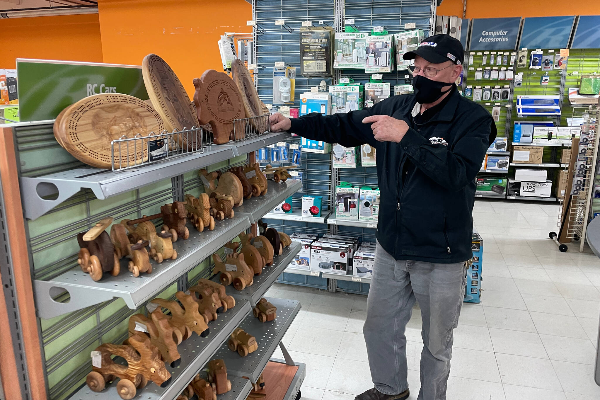 Western Auto Marine manager John Weedman gestures at a selection of locally carved wooden toys available for shoppers at the store. (Michael S. Lockett / Juneau Empire)